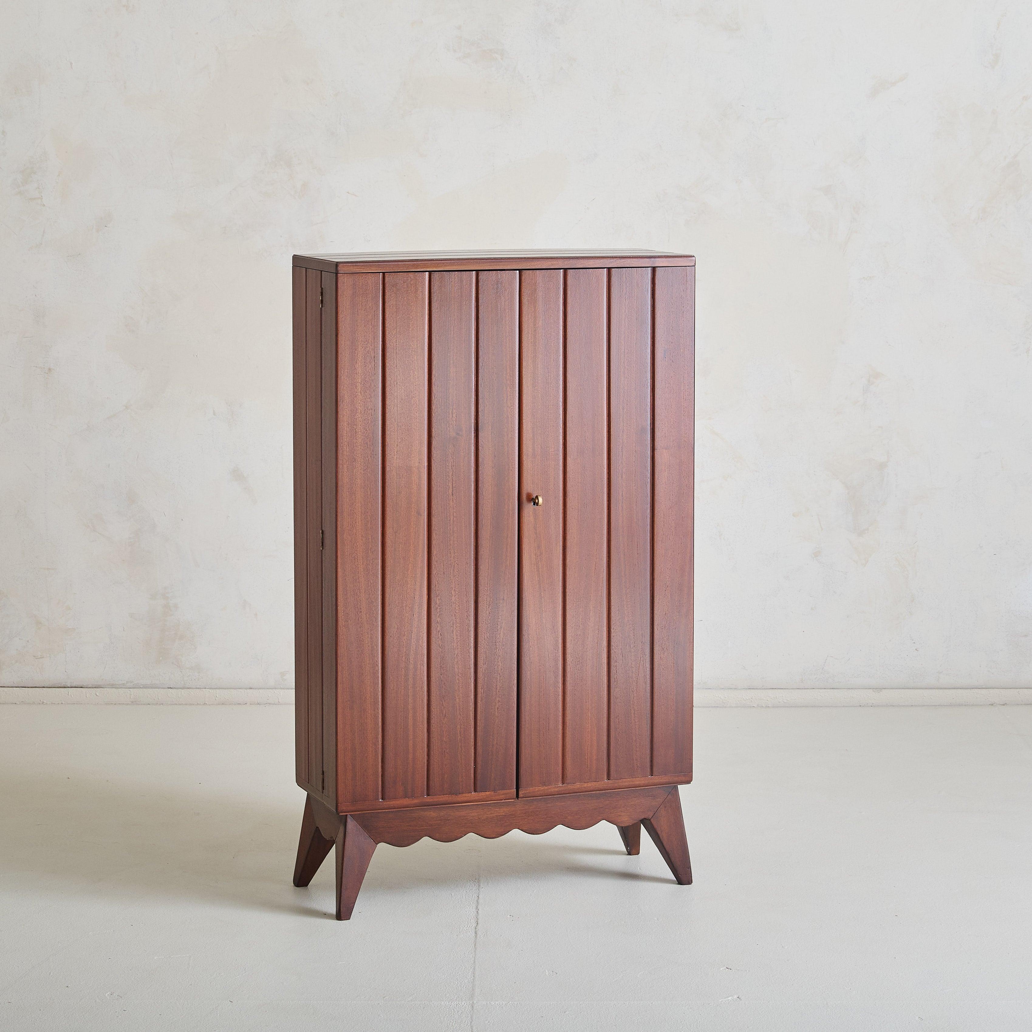 Un meuble de bar italien moderne des années 1960, défini par des lignes épurées et un travail artisanal soigné. Le bois massif aux tons riches présente des rainures le long de la façade et des côtés, ce qui donne une impression de profondeur à sa