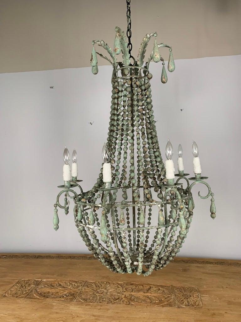 Italian wood beaded painted chandelier with a beautiful worn patina. The fixture is newly rewired with wax candle covers and includes the chain & canopy.