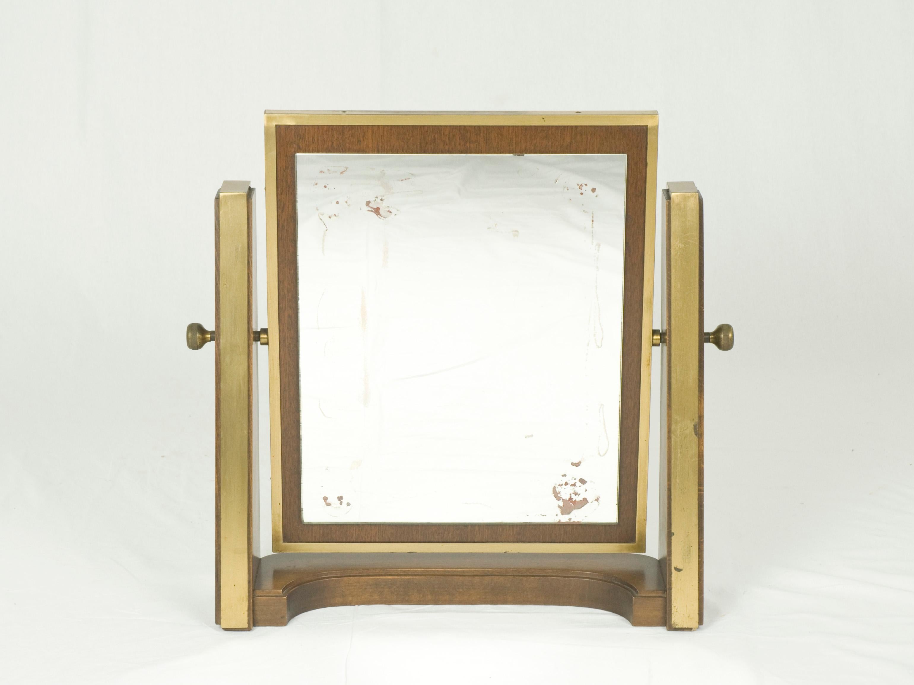 This fine vanity mirror is made from wood and brass with a tilting mirror and usefull brass lockers. It remains in a good vintage condition: Some visible oxidation spots on the mirror (as display in the pictures), patina on the brass.
