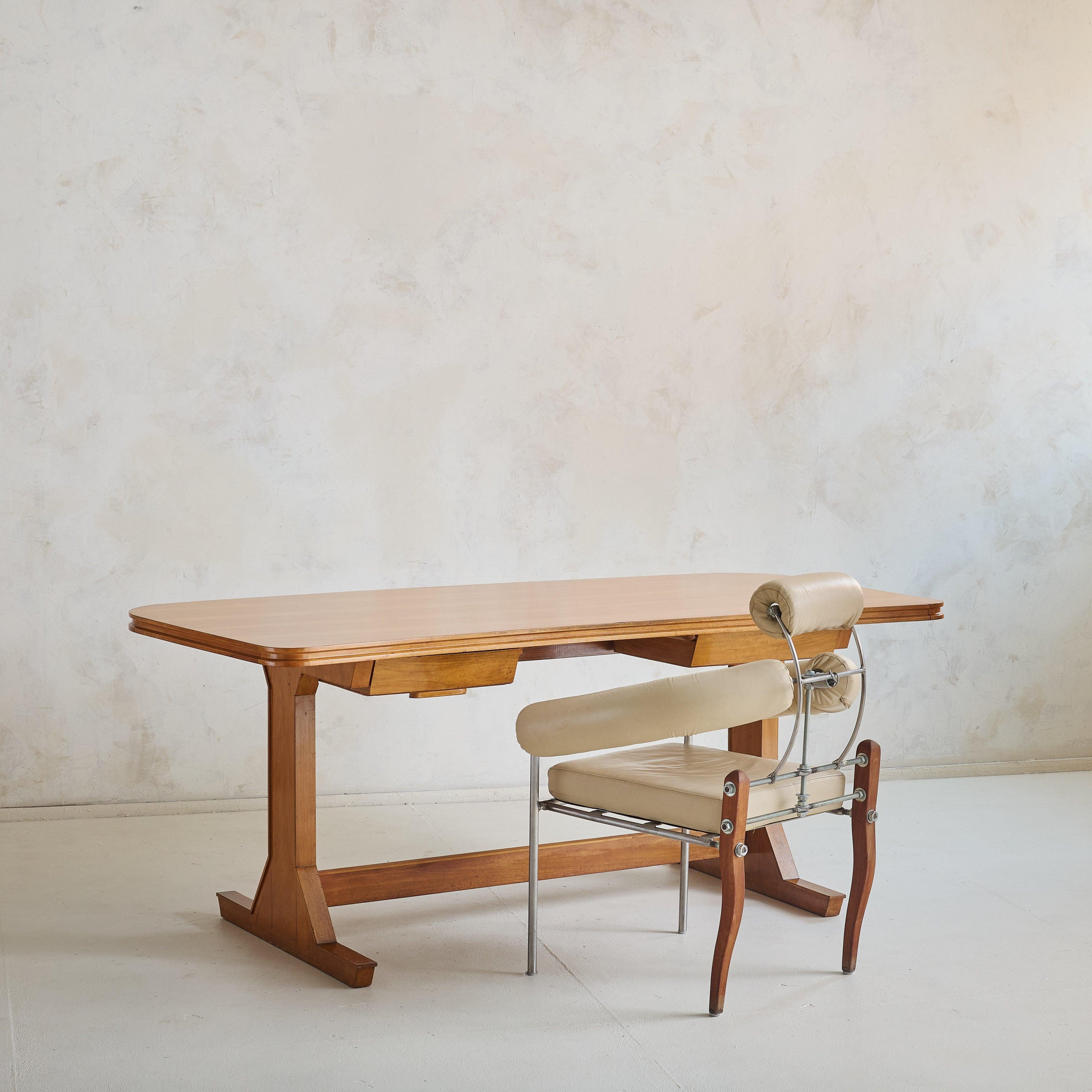 A 1950s Italian desk attributed to Gianfranco Frattini, crafted from warm-toned wood. The tabletop’s subtle curvature and fluted edges offer a soft contrast to the clean, architectural lines of the base. Dual drawers are seamlessly integrated,