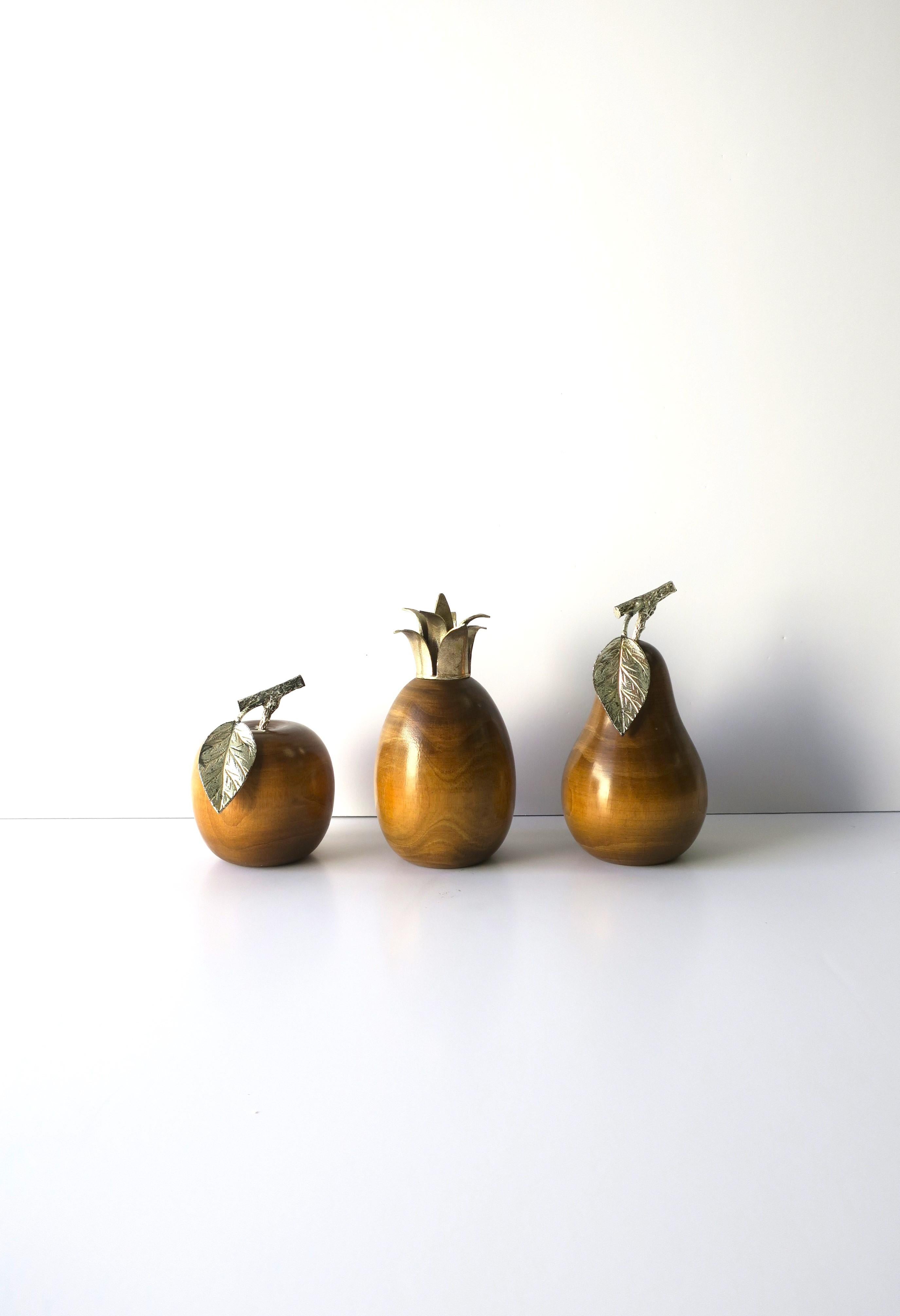 An Italian set of three (3) turned wood fruit sculptures/decorative objects, circa mid-20th century, Italy. A set of three wood fruit sculptures/decorative objects (apple, pineapple, pear), with silver metal detail on each; leaf and stem for apple