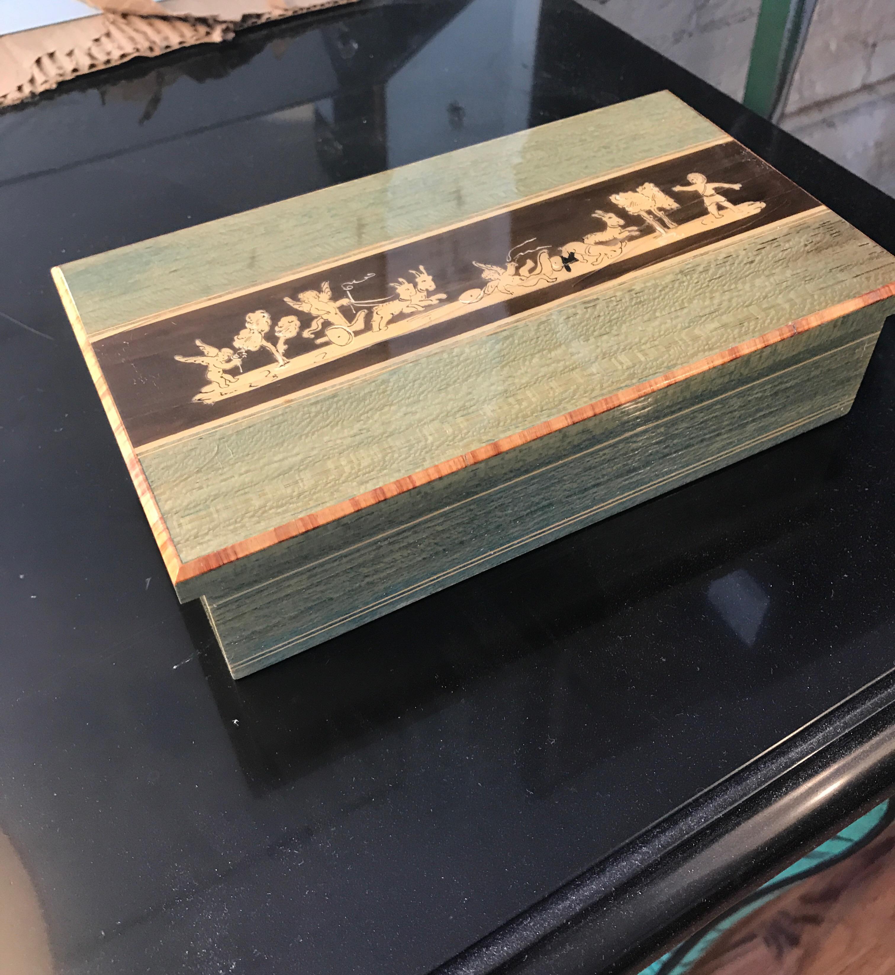 Italian wood marquetry midcentury box. The top features inlaid fruitwood veneer neoclassic
Puti on chariots pulled by goats. Beautiful decorative table top item.