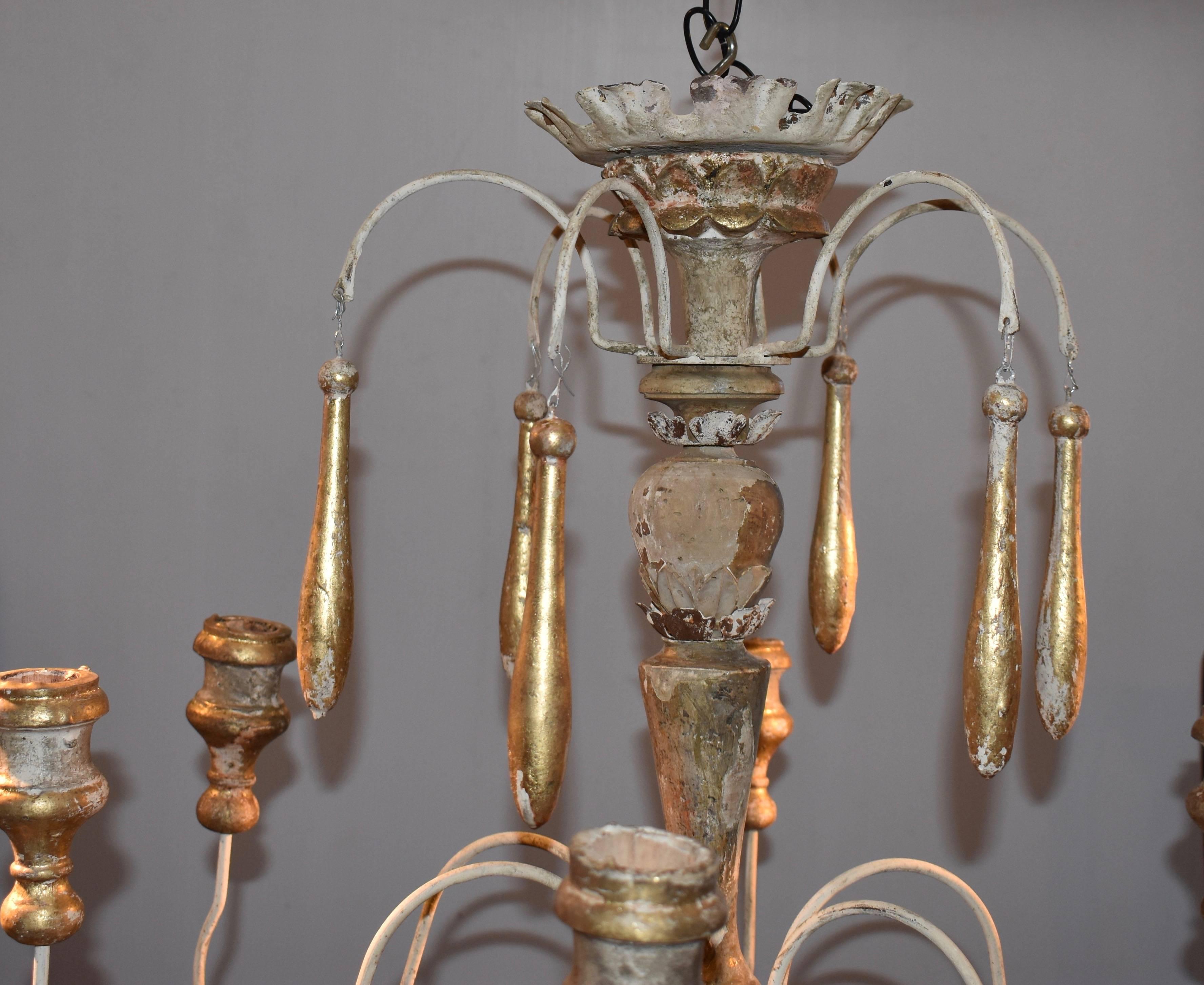 Beautiful wooden chandelier made from 18th century Italian church candlesticks. Great aged patina. Lovely cream white color with hints of aged gilded gold. Not yet wired.