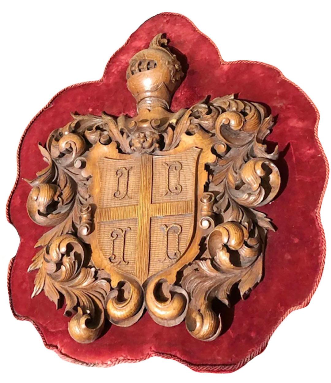 An antique wooden shield mounted on a crimson colored board with velvet border. Carved wooden shield with knight and heraldic carvings. Circa 1870, Italy.