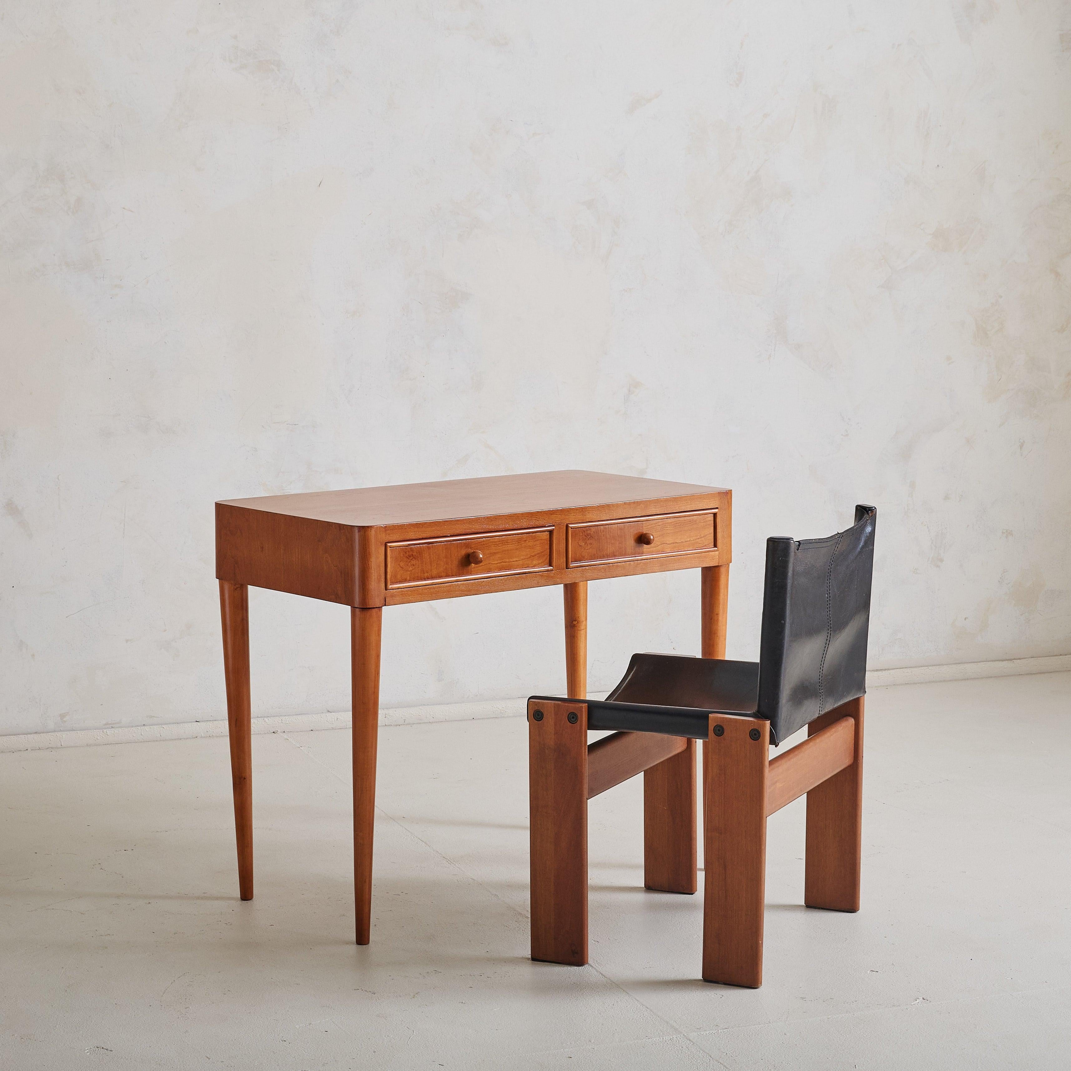 A meticulously crafted 1950s solid wood desk attributed to Paola Buffa. Buffa’s eye for detail is highlighted through its elegant form: a rectangular top with softly rounded corners, supported by four sturdy wooden legs. Two drawers with spherical