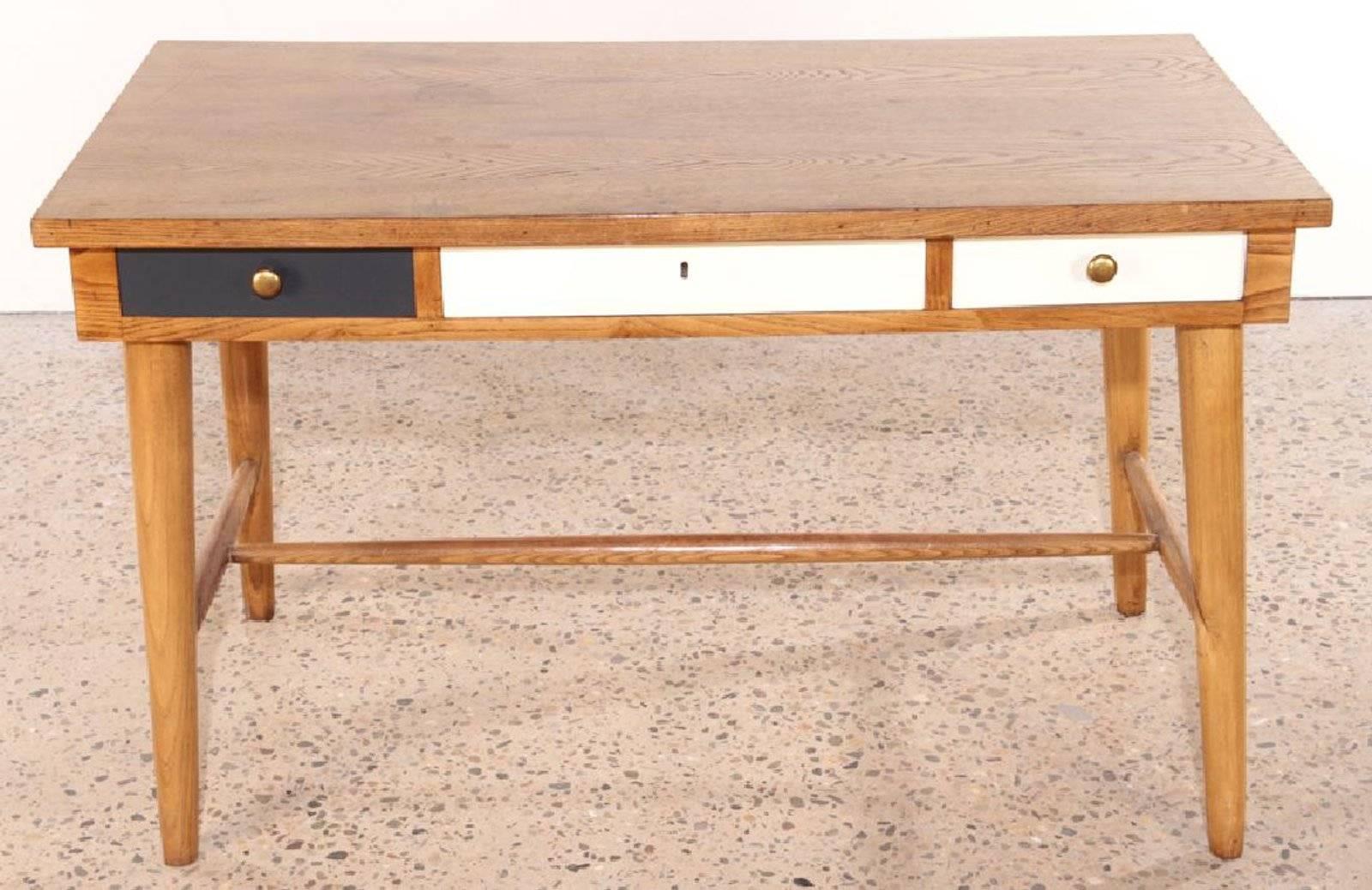 This unique Italian writing table in the manner Gio Ponti, is made of oak and features three drawers, one black and two white. A very stylish piece.  Surface of desk is worn.

Measure: 27.75