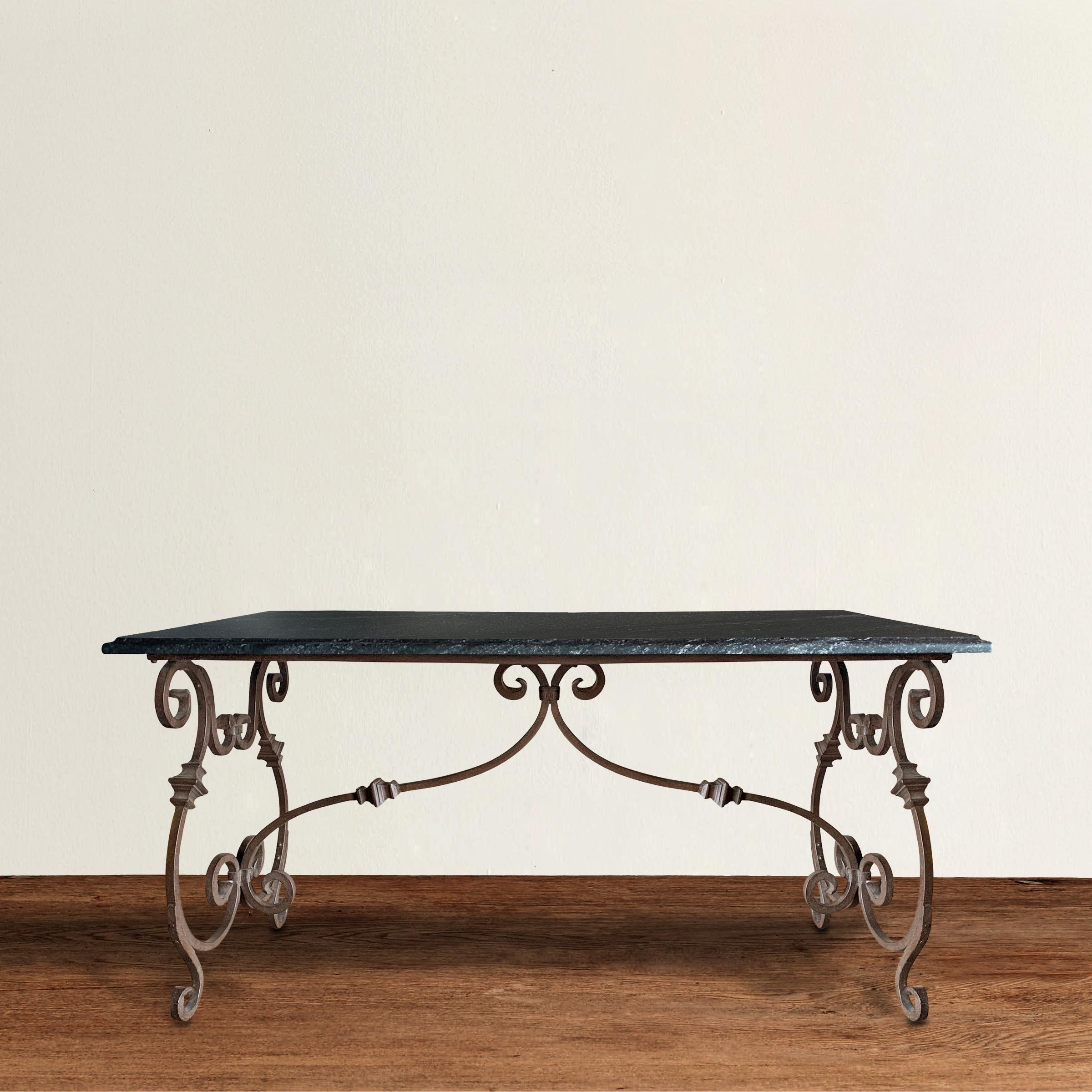 A fantastic late 20th century Italian wrought iron table with a wonderfully scrolled base and a black leathered granite top with an ogee edge. The table is the perfect height for a desk, writing table, or dining table, but also works perfectly as a