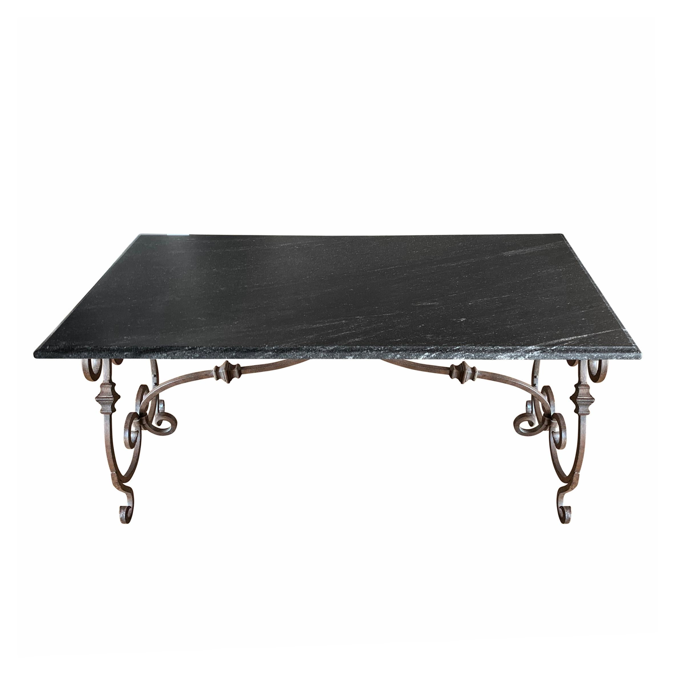 Une belle table italienne de la fin du 20e siècle, avec une base en fer forgé à volutes et un plateau en granit noir avec un bord en ogive. La table est à la hauteur parfaite d'un bureau, d'une table de travail ou d'une table à manger, mais elle