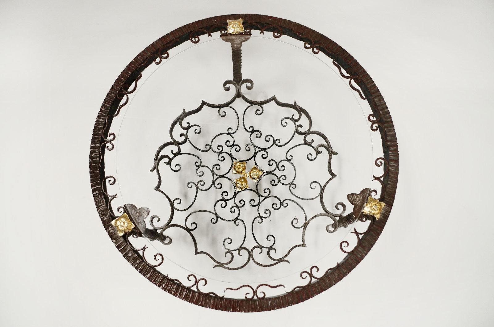 Table basse ronde d'extrémité en fer forgé décorée de volutes et de rosaces dorées. Pieds tordus reliés par un brancard avec le même décor. Dessus en verre.
Travail italien, vers 1950.