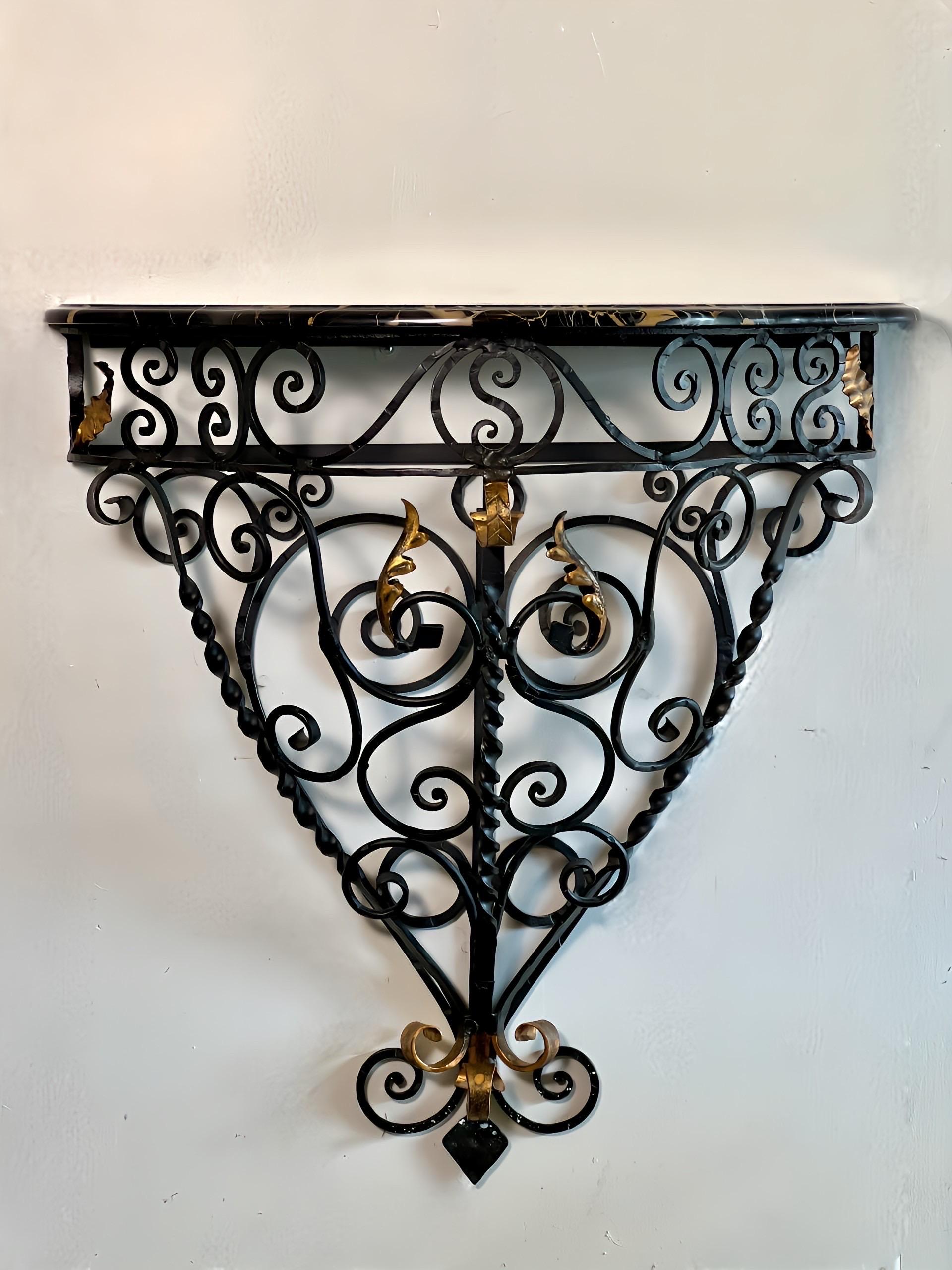 Vintage 1960s Rococo style wrought iron wall mount console table with marble top, made in Italy.  Stunning console having a black wrought iron body with gold leaf accents and a serpentine shaped black marble top with gold/white veining and sculpted