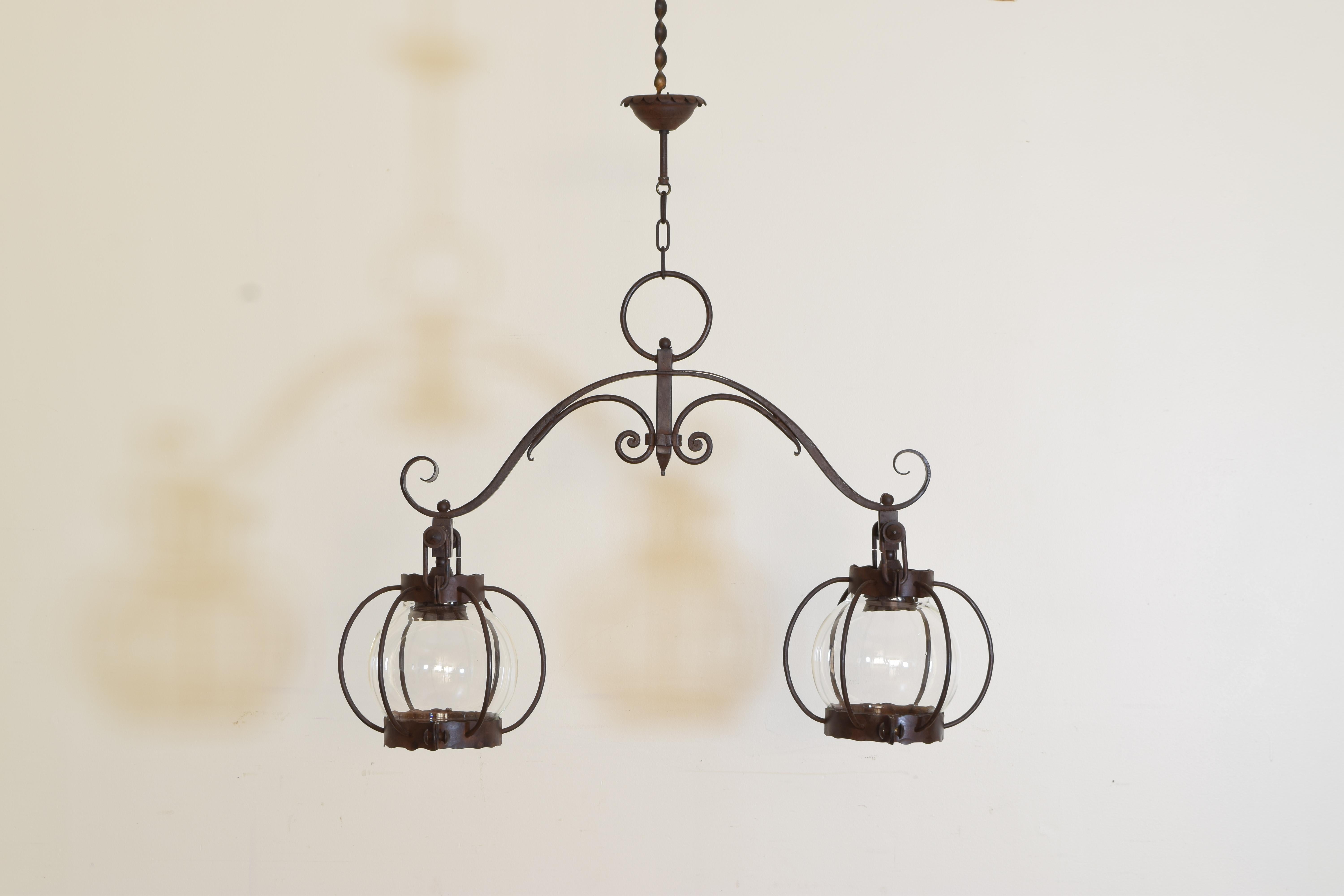 Consisting of two “caged” glass globes hanging from an elaborately wrought iron support, the craftsmanship exceptional and the glass globes original, kitchen island, billiards, among the applications.