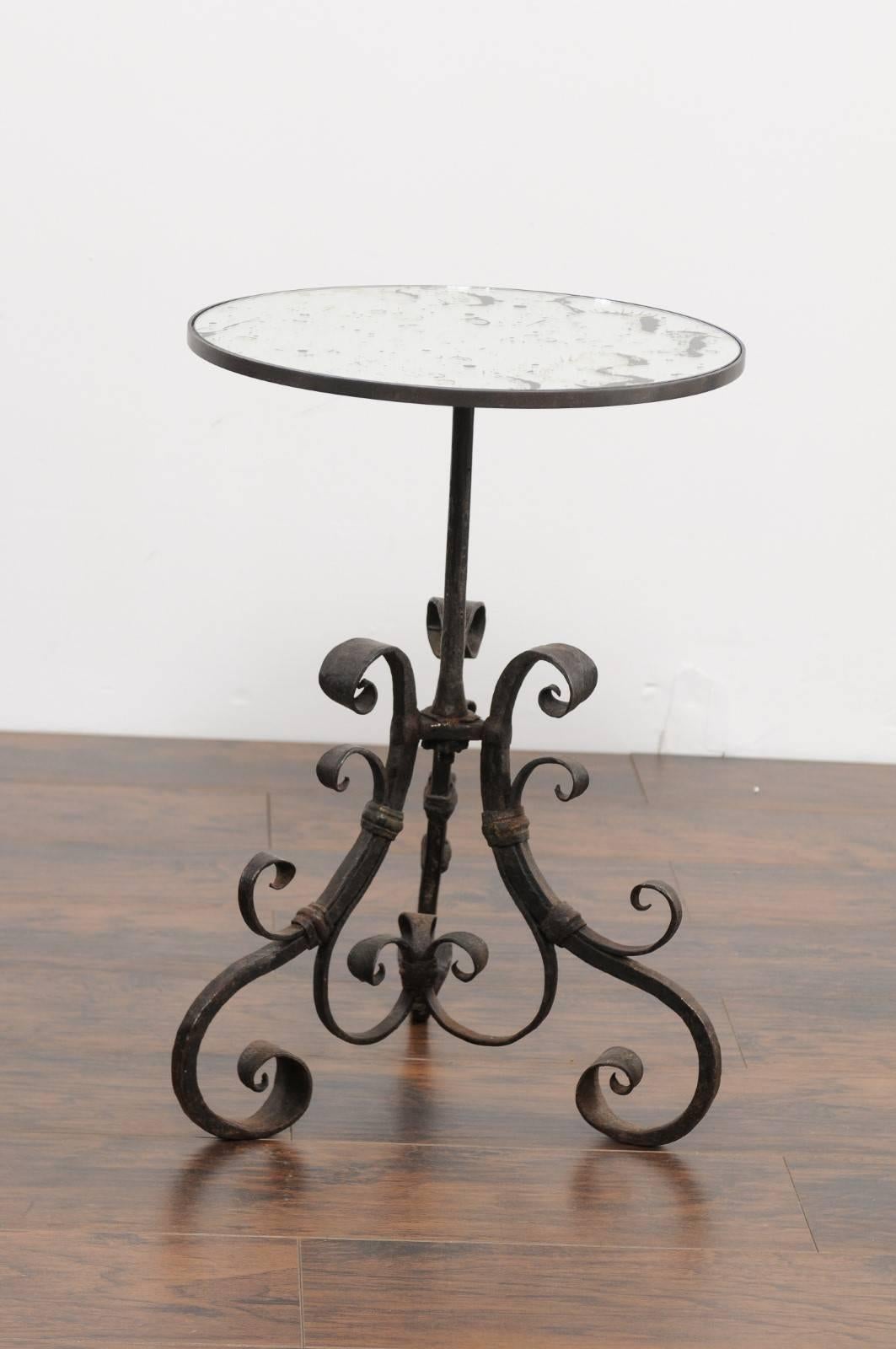 An Italian wrought iron round pedestal side table with antique mirrored top from the second half of the 19th century. This Italian side table features a circular top supporting a nicely aged antique mirror. The table is raised on an exquisite