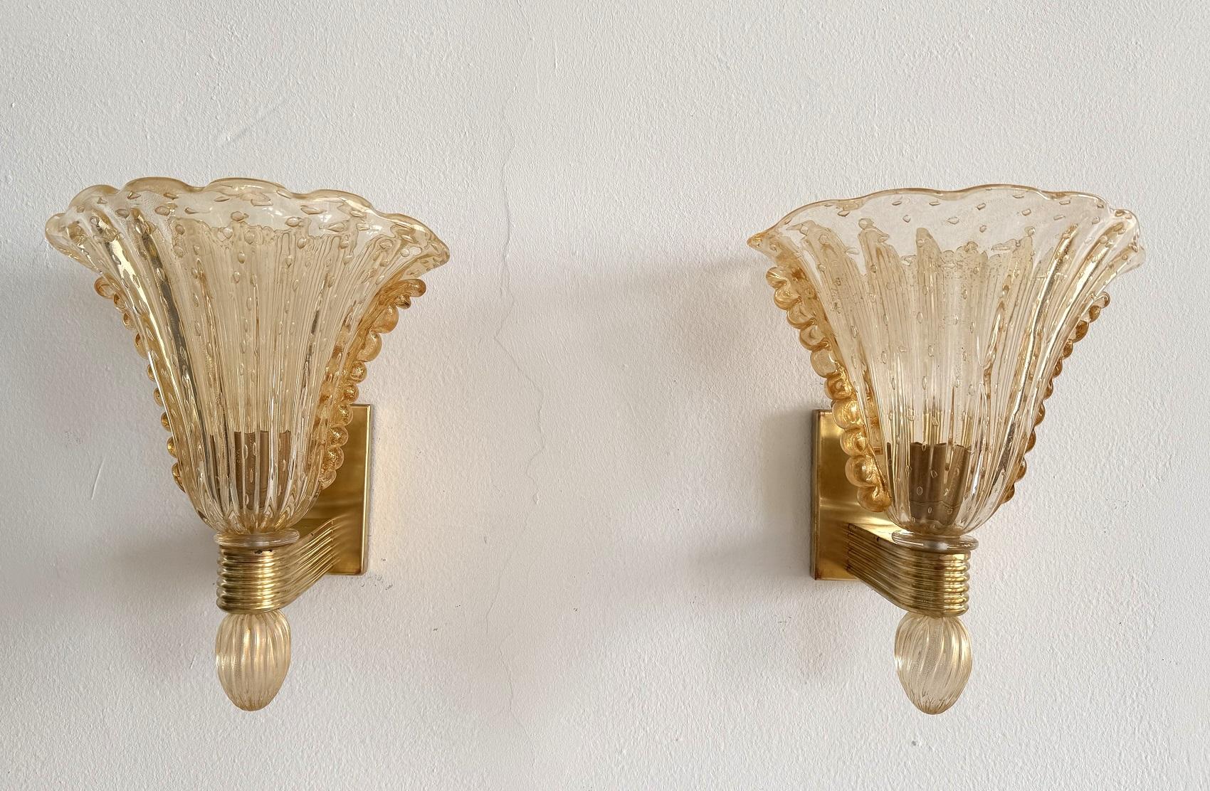 Magnifique ensemble de deux grandes lampes murales en verre de Murano et laiton. Fabriquées en Italie par Barovier&Toso. 
Une solide base en laiton supporte les lourds verres ondulés de Murano de couleur ambre. 
Le laiton est signé Barovier&Toso
