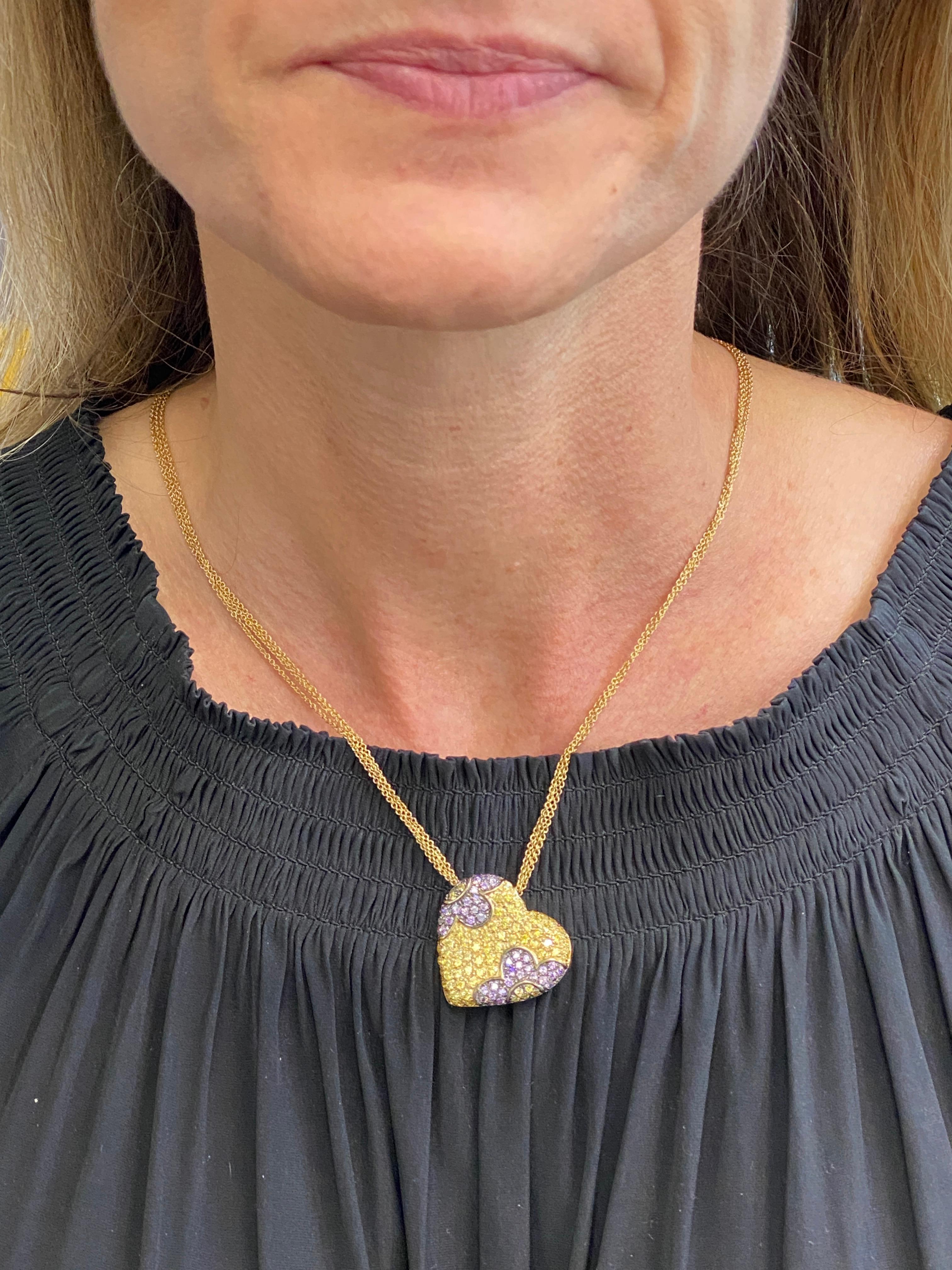 Colorful Italian heart pendant fashioned in 18 karat yellow gold. The pendant features round brilliant cut yellow & purple sapphires in a floral design. The pendant measures 1.0 x 1.0 inch, and the multistrand necklace measures 17 inches in length. 