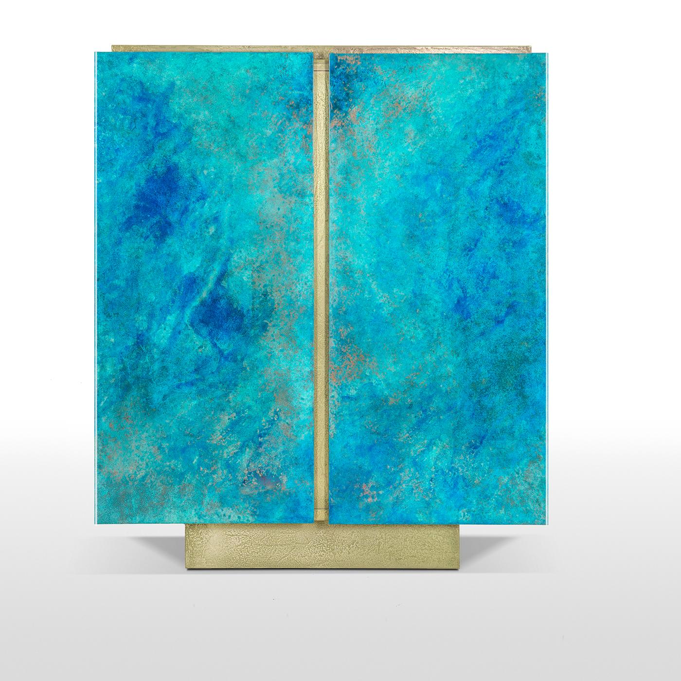 Sophisticated and eye-catching this versatile cabinet was completely handcrafted. Its structure in blockboard and MDF features a plinth base and a generous storage space. The two-door panels are hand painted in turquoise and ocean blue with a glossy
