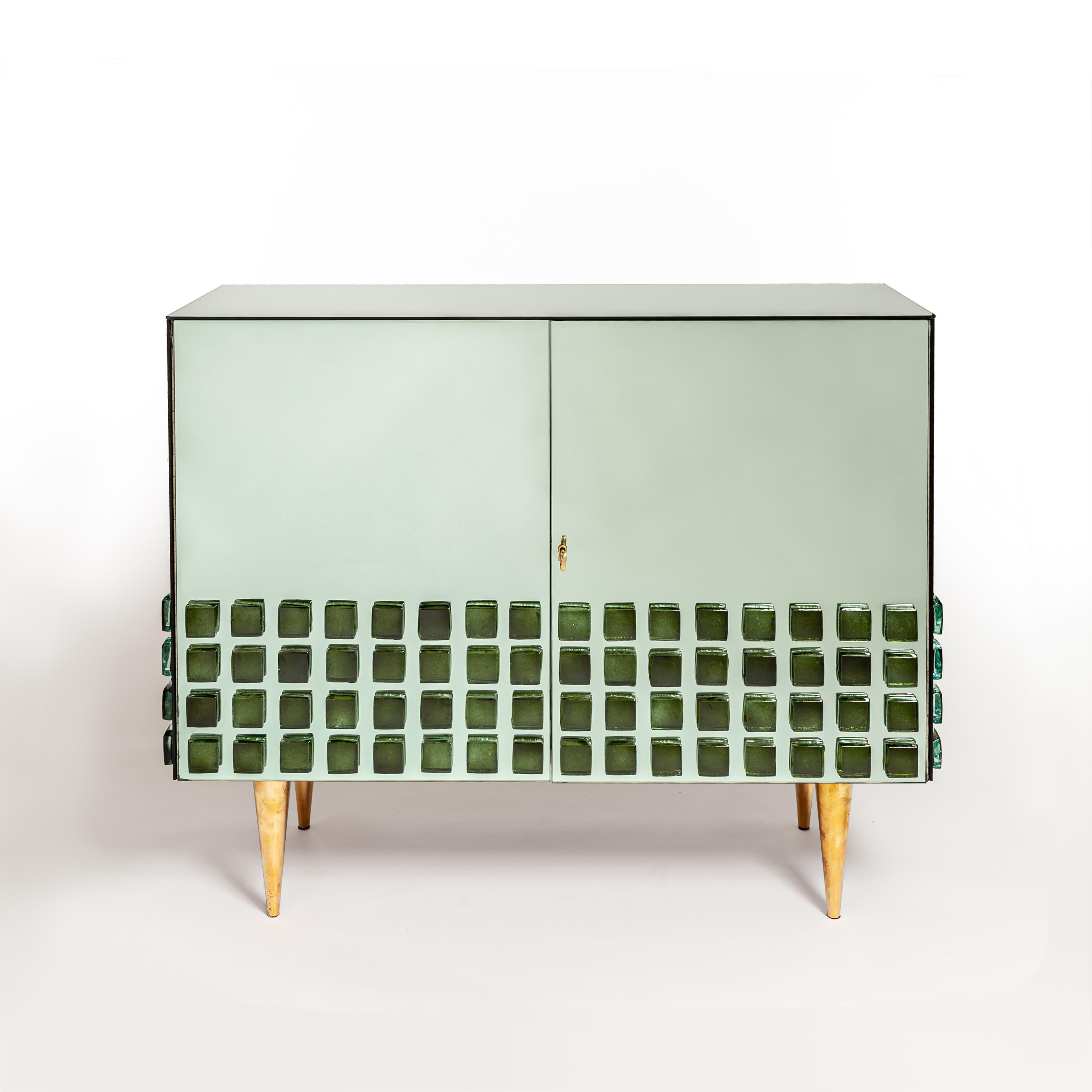 Italian 2-doors mirrored sideboard in the style of Roberto Giulio Rida.
Solid wooden body in beechwood veneered with green mirror glass - all edges are faceted.
In the lower third, hand-cast thick opal glass stones (medallions) in emerald green are