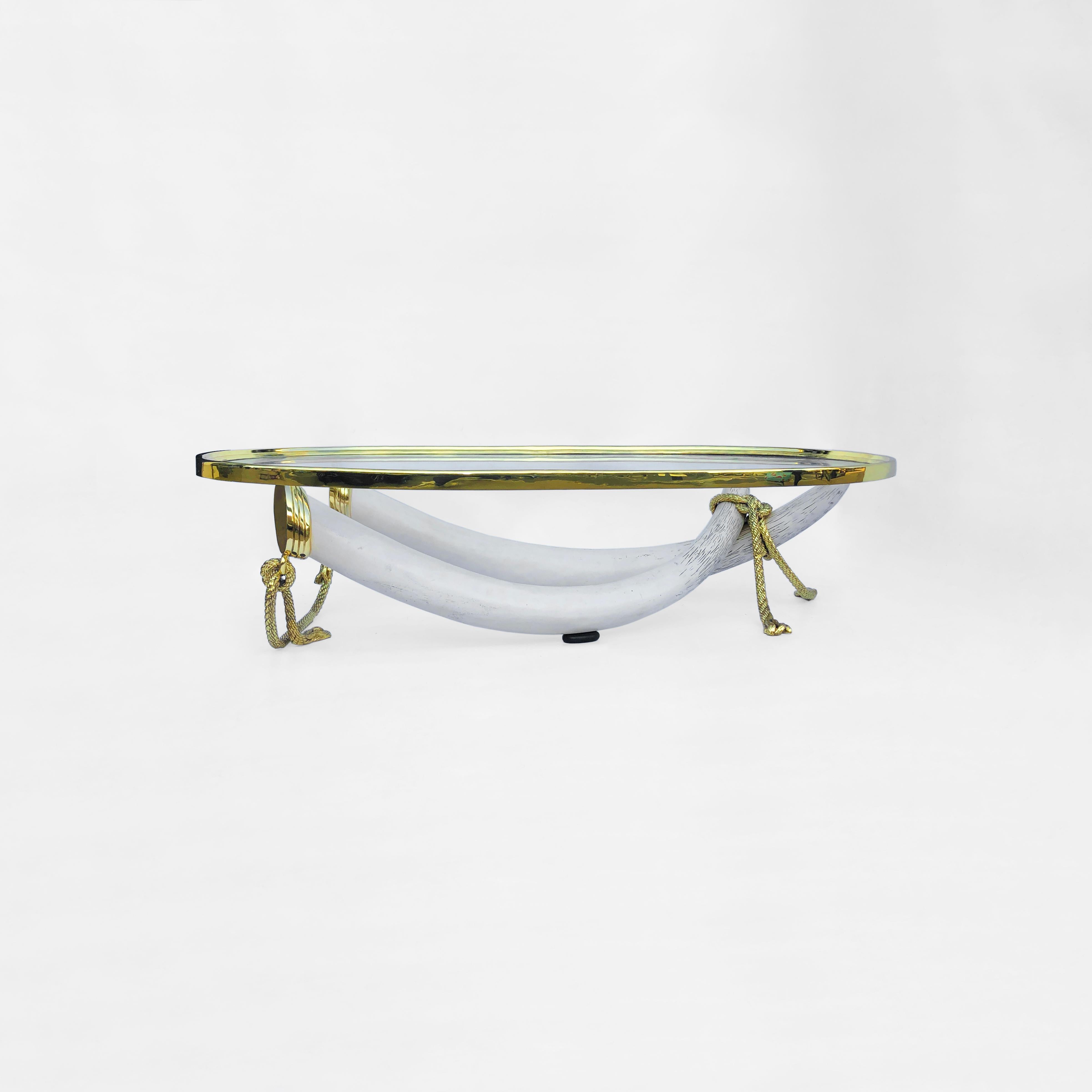 One of the most impressive pieces we've seen in a long time, this massive coffee table from Spanish designers Valenti consists of two crossed faux-ivory tusks supporting a large oval-shaped brass and glass top. The tusks are made of resin and