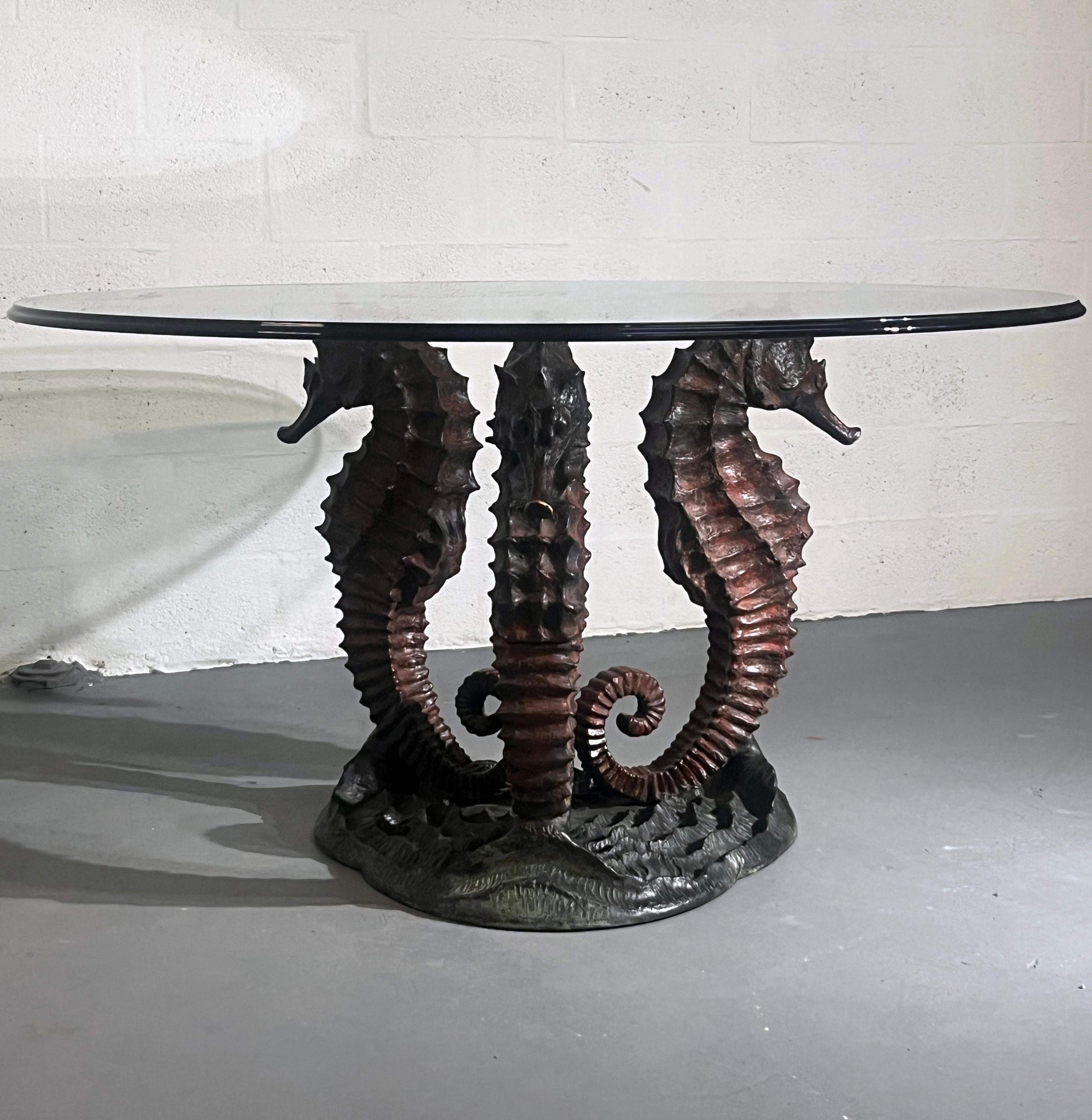 An exceptional sculptural coffee table by Italo Valenti, Italy, circa 1970s.
The striking base is composed of three monumental seahorses in patinated bronze, their curled tails and textured bodies rising from a rocky seabed. The naturalistic