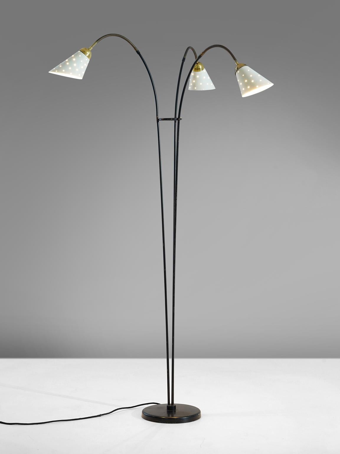 Floor lamp with colored shades in white metal and brass, Italy, 1950s.

This floor lamp is built up of one deep black foot from which one brass stem arises that sprout into three arms. The arms each end in a metal shade, all featuring an off-white