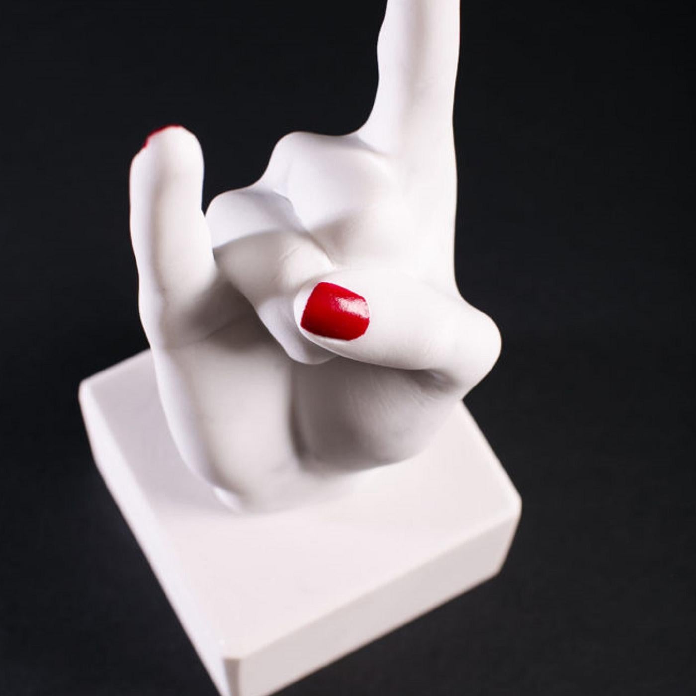 Provocative and unconventional, this sculpture is crafted entirely by hand of white Carrara marble and is supported on a cubic base of pure white marble. It reinterprets the extending finger, symbol of contempt in Western cultures, substituting it