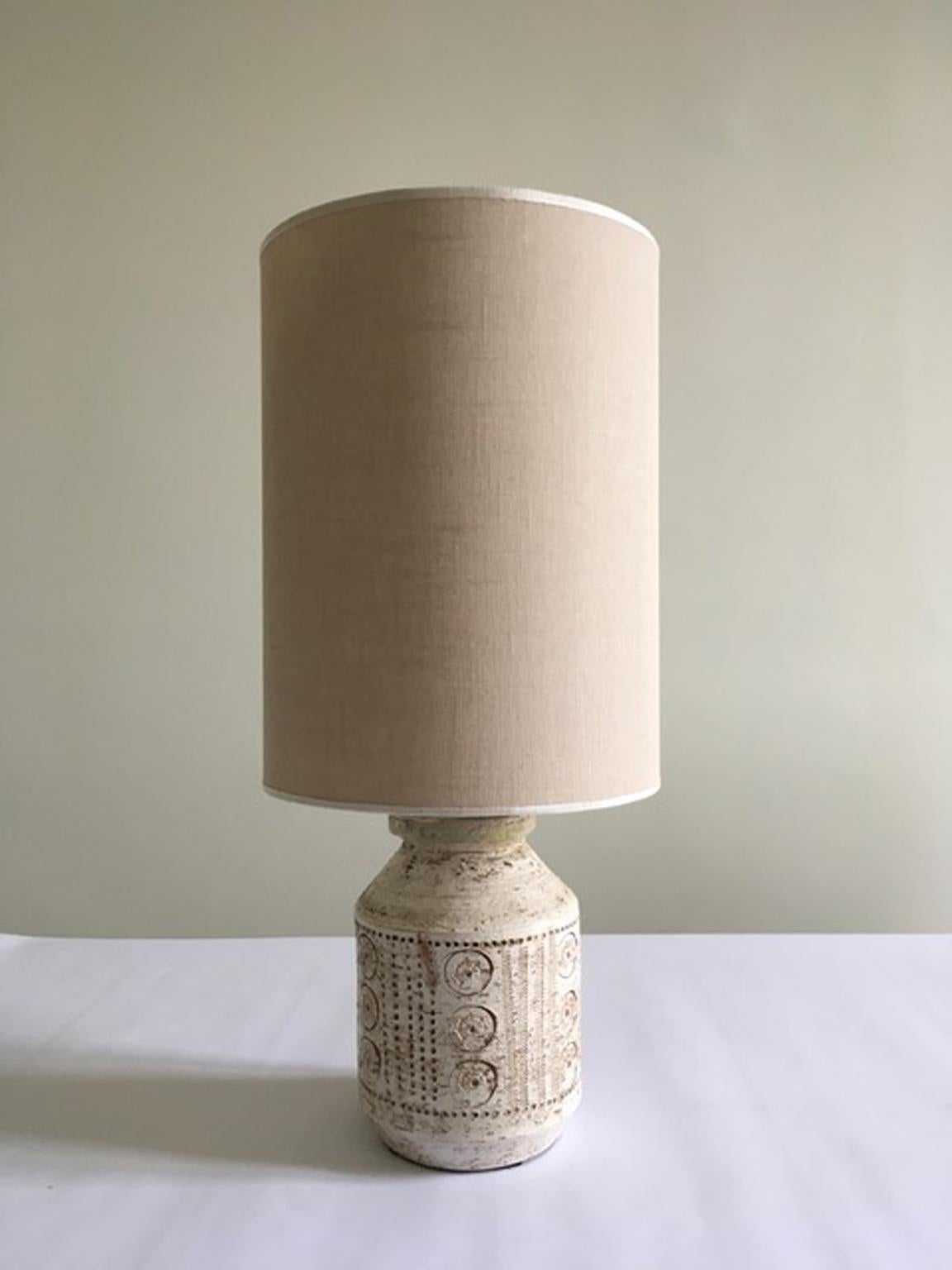 This is a stunning Italian ceramic table lamp made in 1960/1969 circa.
The white ceramic body has an organic shape and it is engraved on the surface with  abstract drawing that can be defined as tribal graffiti. This is a table lamp trendy and