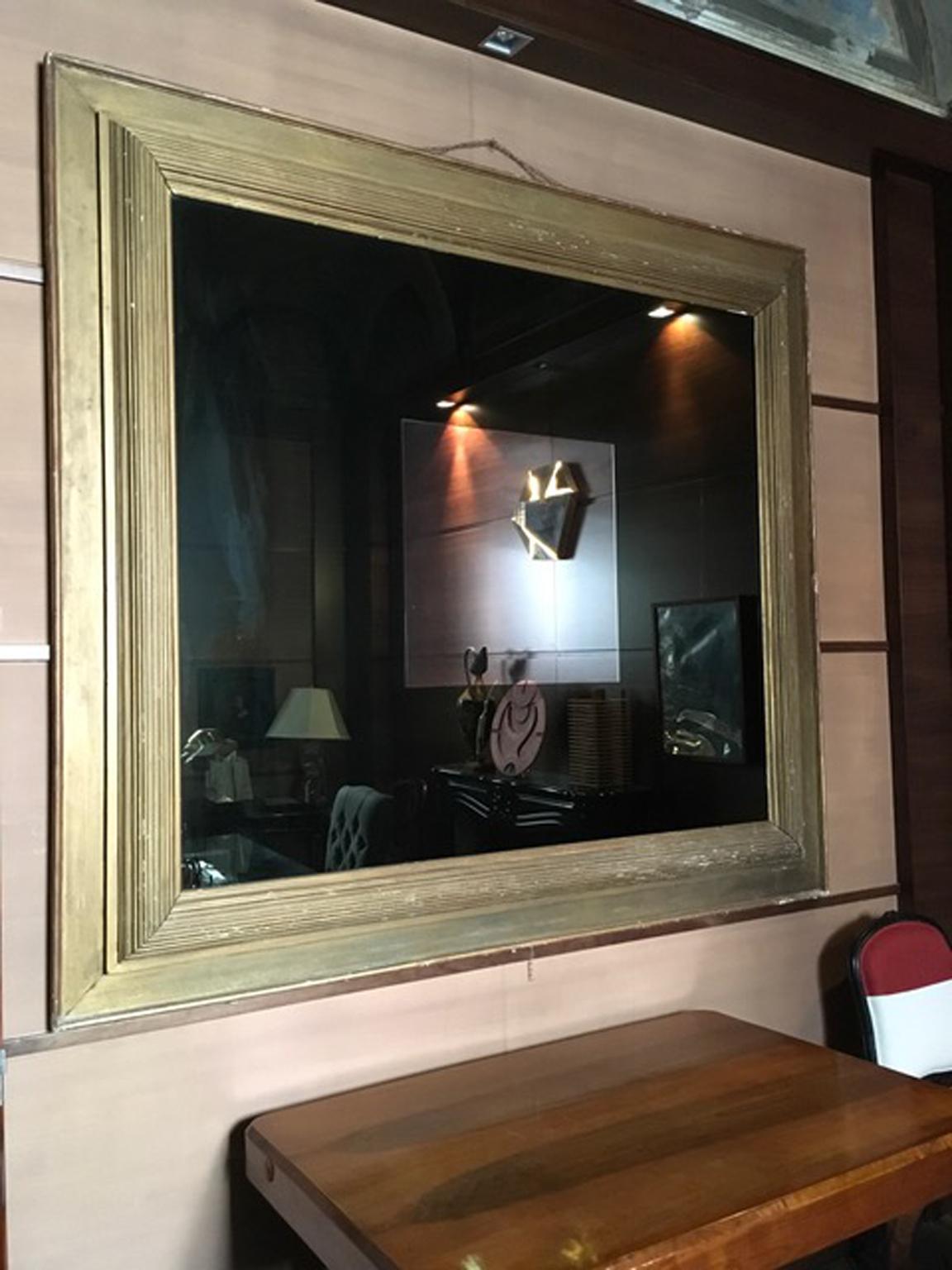 Dieser atemberaubende postmoderne Spiegel hat einen goldenen Holzrahmen aus der Zeit um 1960. Der riesige geräucherte Spiegel hat in der Mitte ein klares Spiegelquadrat. Das Ergebnis ist ein einzigartiges Stück im Stil der italienischen