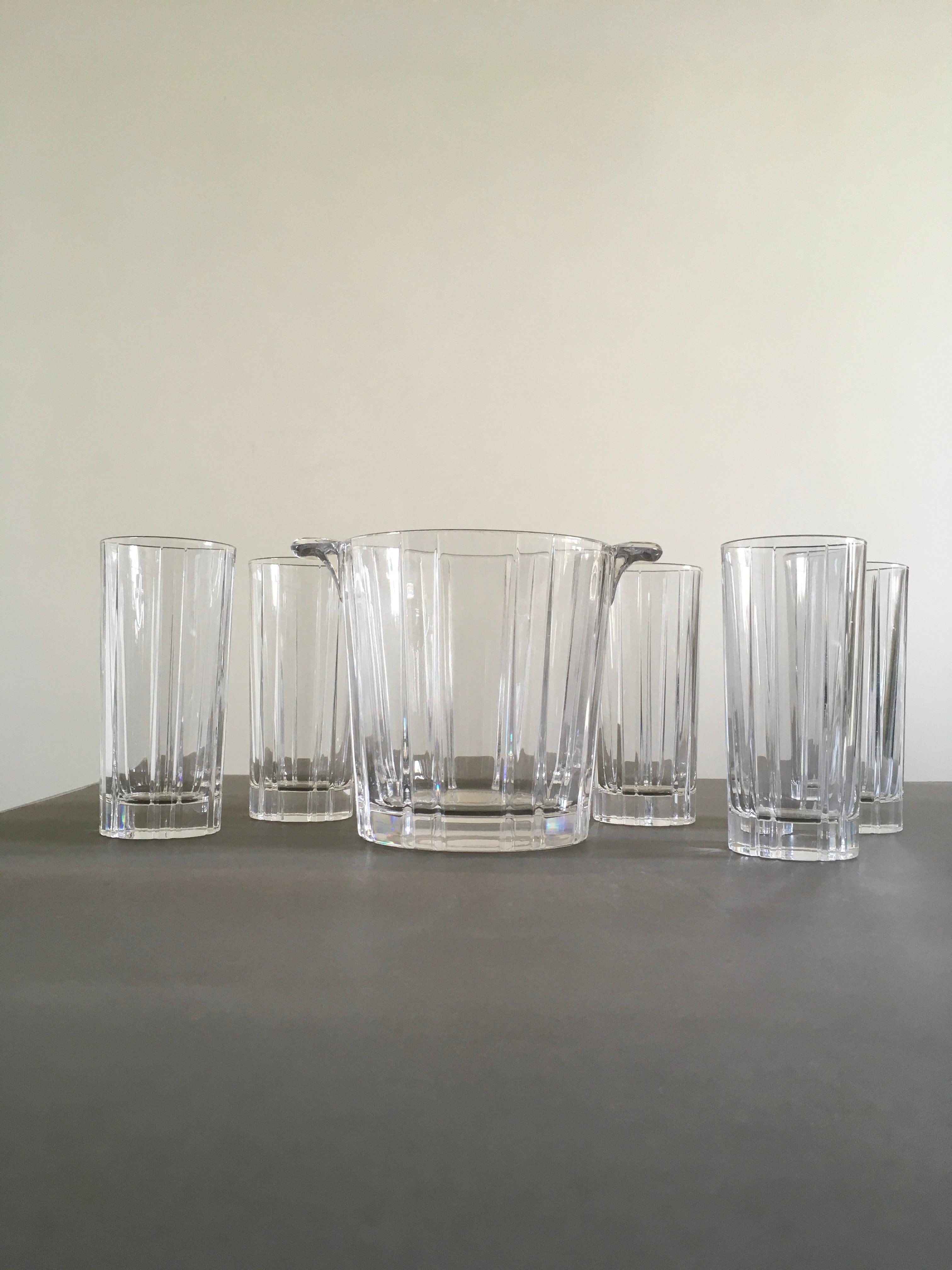 Este exquisito juego de 5 vasos de bar transparentes, con su cubitera, personifica el estilo italiano de esta época. La superficie rayada es un elegante patrón que caracteriza a este juego, cada vaso muestra la perfecta armonía de forma y función, y