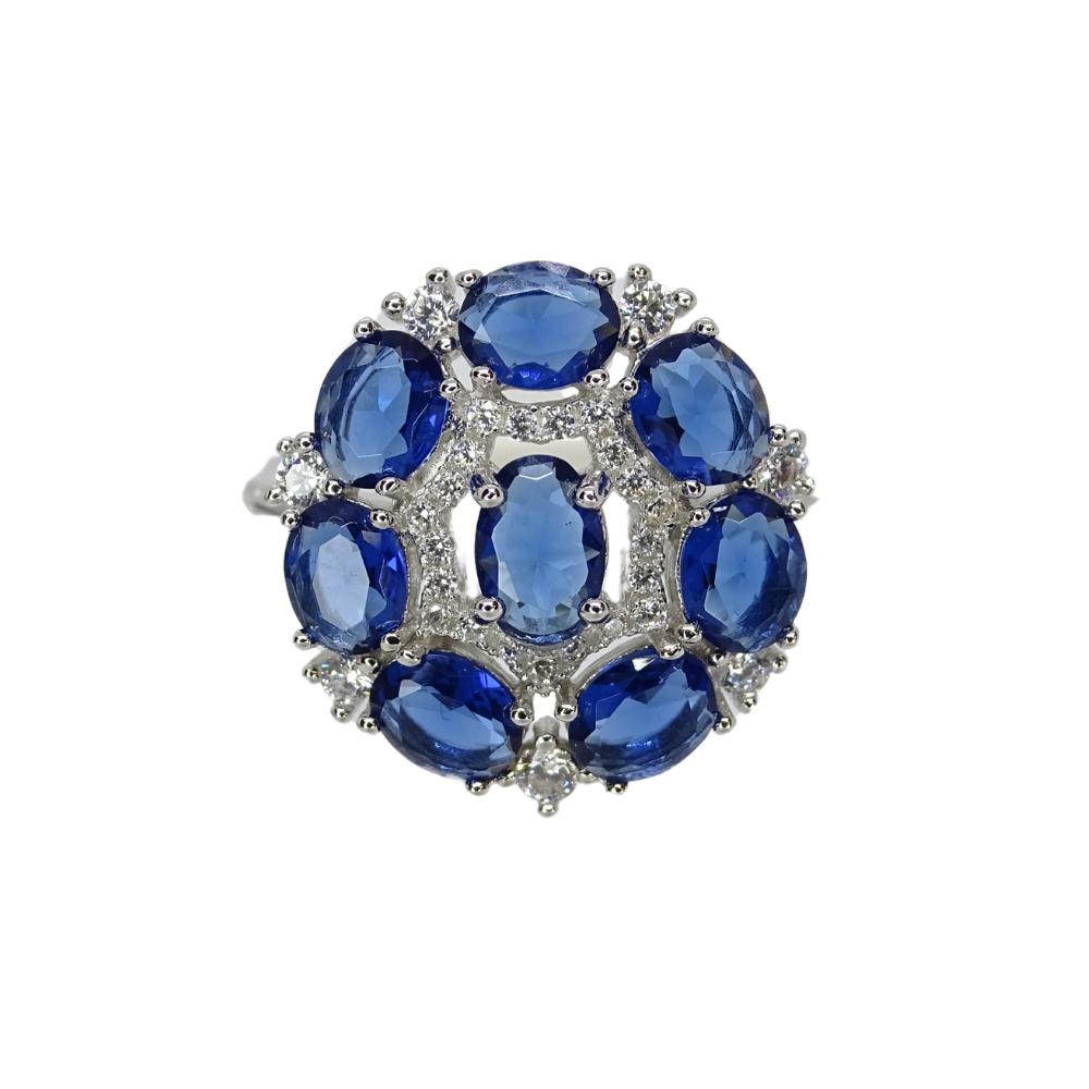 One of a kind and very refined and elegant rosette set in 925 silver. Its rosette shape is composed of eight oval-cut sapphire root stones, adding dynamism and symmetry to the composition. The center stone is prong-set and features a border of small