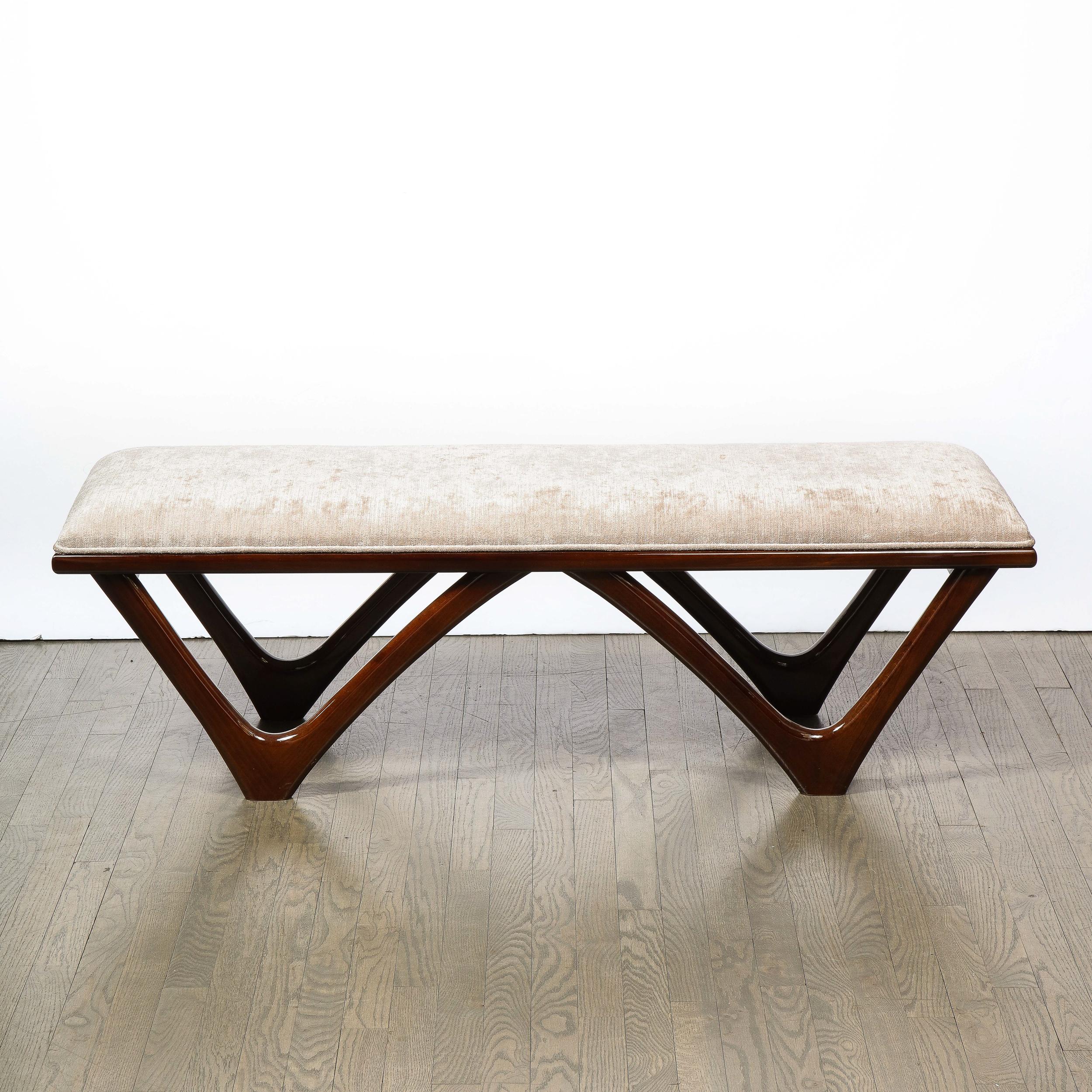 This elegant Mid Century Modern walnut and taupe bench was realized in Italian, circa 1950. It features a sculptural high gloss walnut base composed of two adjoining inverse arch 