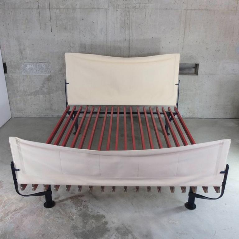 Original et TRES RARE, lit EPIC, par le maître Achille Castiglioni en 1984.  Lattes en bois laqué rouge, pieds en métal peint en bleu foncé, tête et pied de lit en toile recouverte d'un épais tissu crème.

Convient pour un matelas de 200 x 180