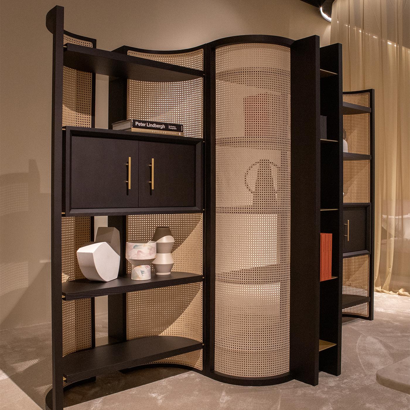 Edle Oberflächen und umhüllende Kurven kennzeichnen dieses Bücherregal, dessen subtiles skulpturales Design an raffinierte orientalische Atmosphären erinnert. In zwei geschwungenen Rahmen aus moka-gebeizter Esche setzt Vienna straw einen