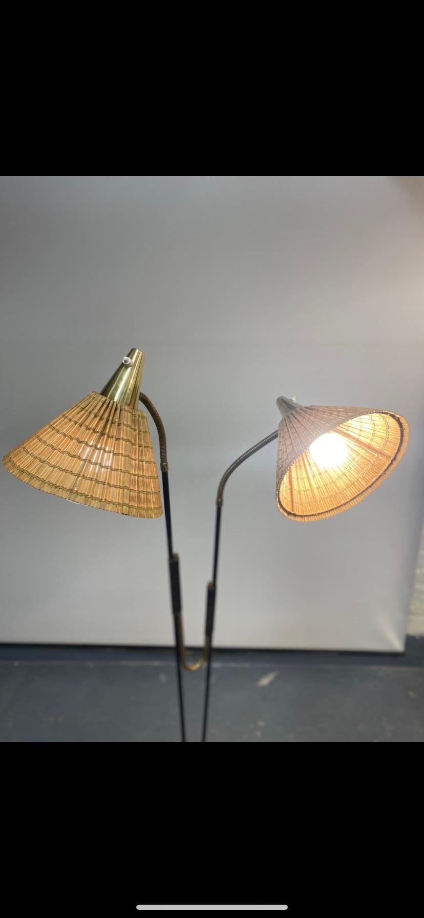 A somewhat rare Itsu floor lamp with a beautiful design displaying two distinct light heads, that can be adjusted to almost any direction desired. The black painted metal, and the brass parts suit each other perfectly in this elegant and quite