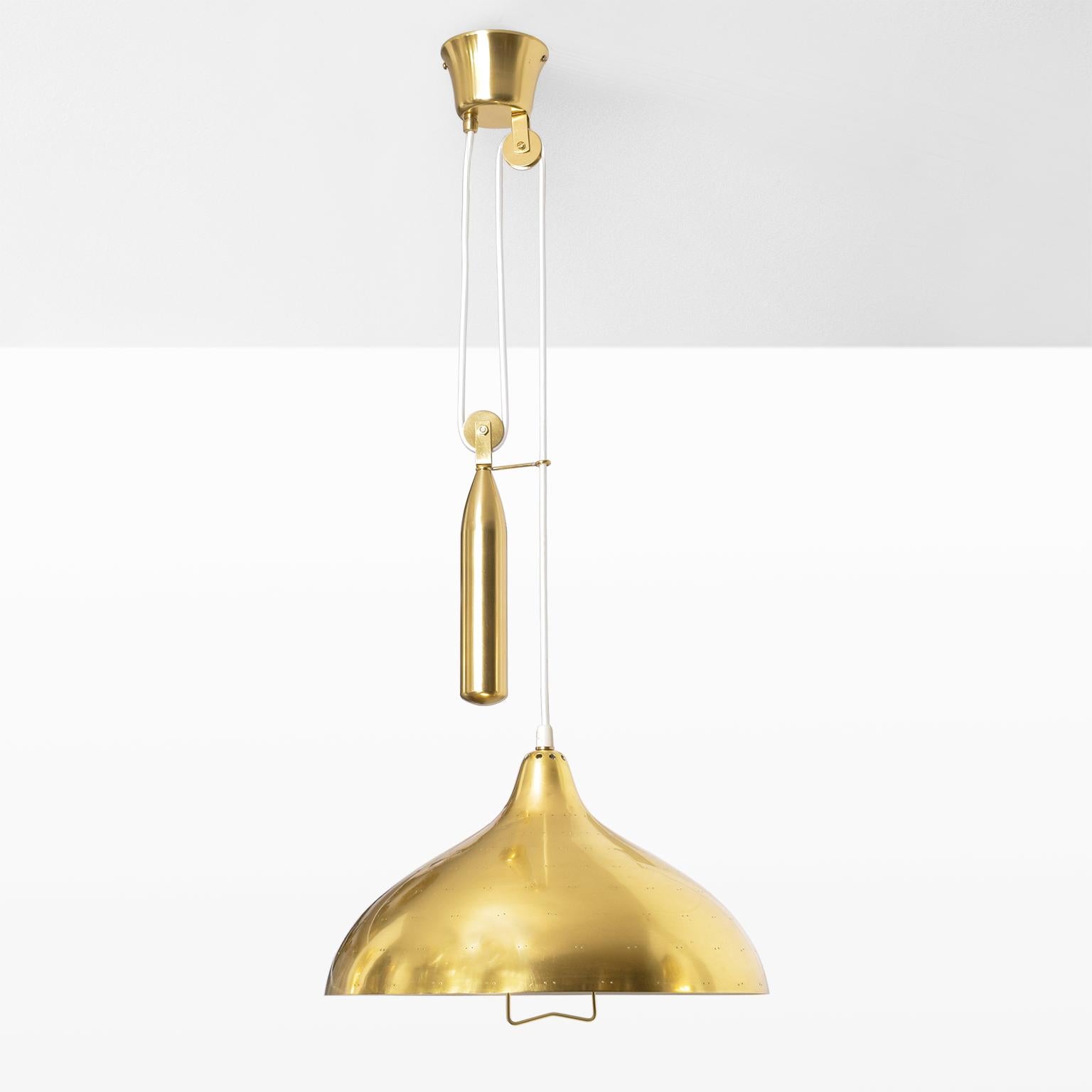 An adjustable pendant fixture with a perforated shade and counterweight mechanism. Newly restored, polished and lacquered shade, inner shade newly painted, newly rewired for use in the USA with a single Edison base socket. Made by Itsu, Finland