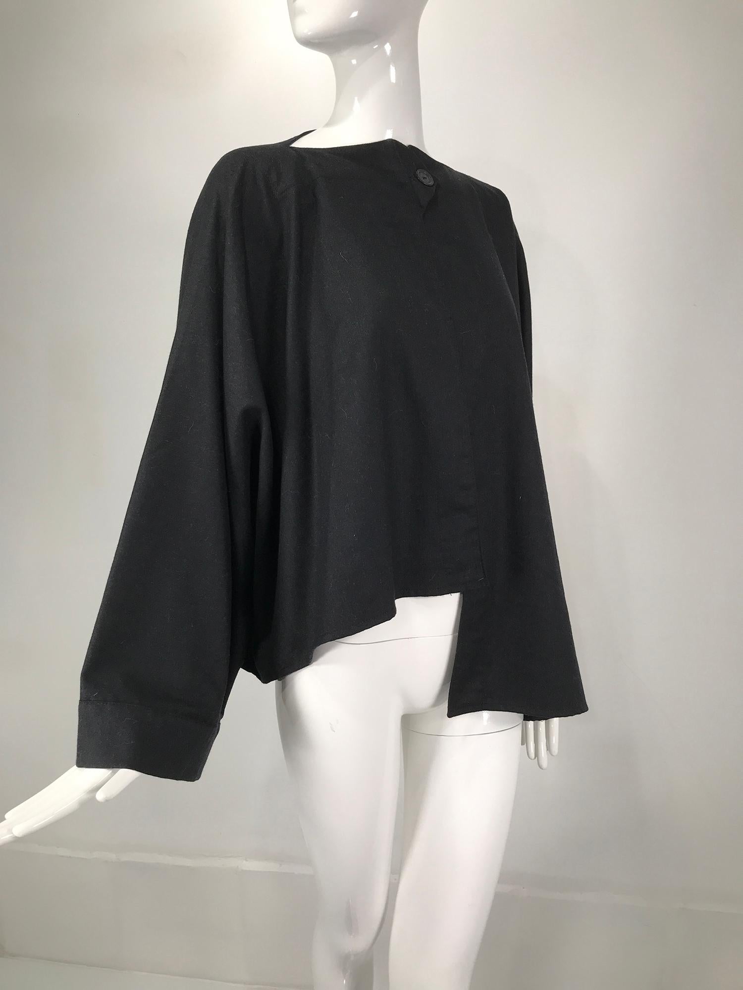 Ivan Grundahl black wool kimono sleeve asymmetrical hem jacket. Single button closure at the neck, button & tab. Fine, lightweight wool with wide kimono sleeves, open front, full flared back. Unlined. Perfect for layering. Fits a size small-medium.