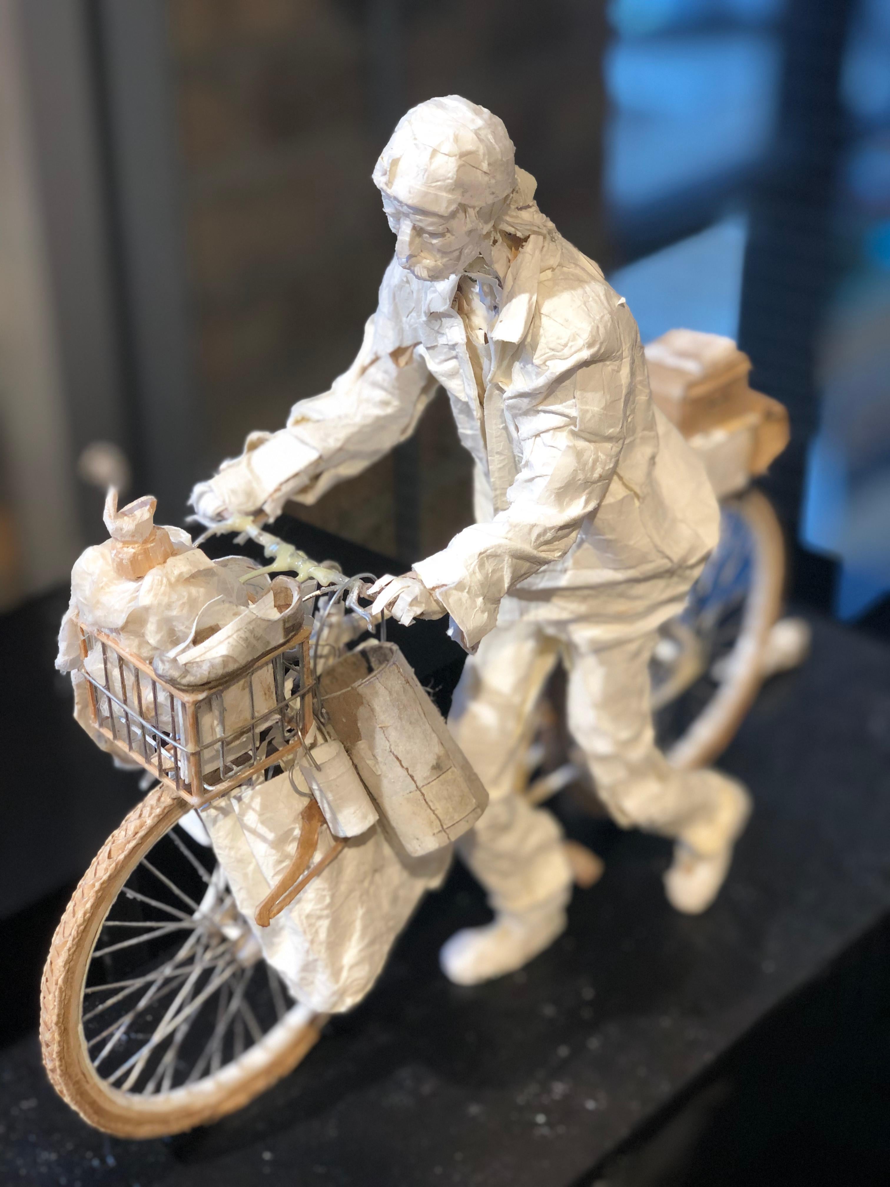 This realistic sculpture is created from scraps of paper and glue.  Some of the details in the bike are made using simple materials such as wire, string and wood.  The sculpture is inspired by the characters found in cities around the world who pick