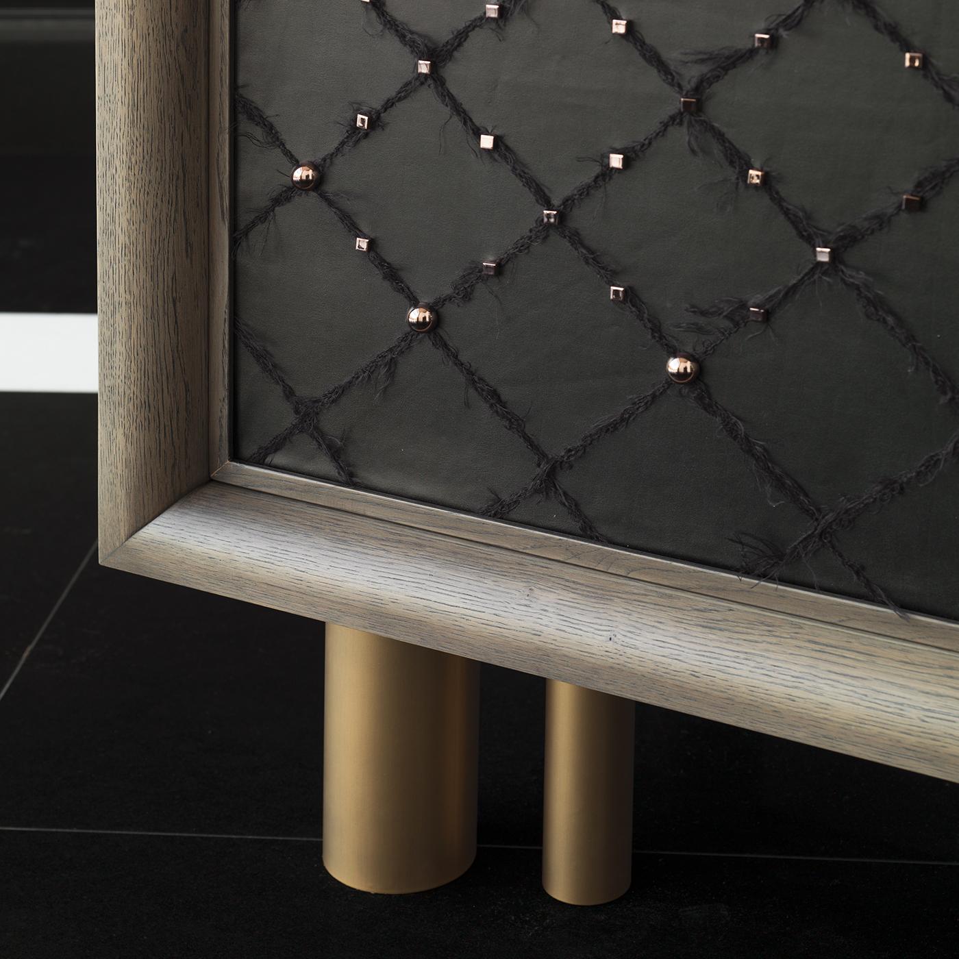 The Ivo black cabinet combines a chic contemporary frame with extravagant finishings. Handcrafted in oak, the cabinet features a cool gray finish and bronze-colored metal legs. Containing three drawers and two glass shelves with a mirrored backing,