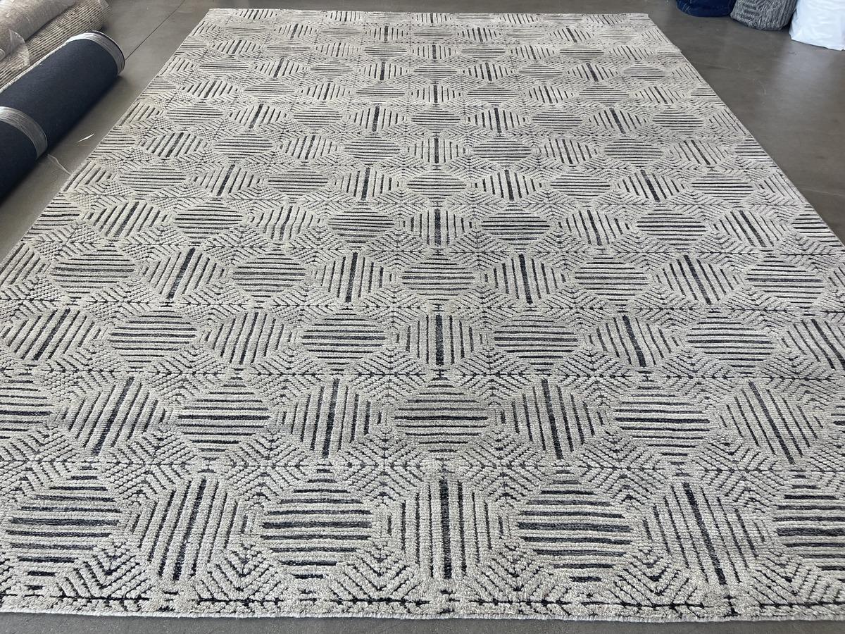 Looking to add a touch of visual excitement to your space? Contrasting ivory pile and charcoal weave create a fascinating geometric pattern in this large area rug from the popular Mystique line. Durable wool construction. Hand made in India using