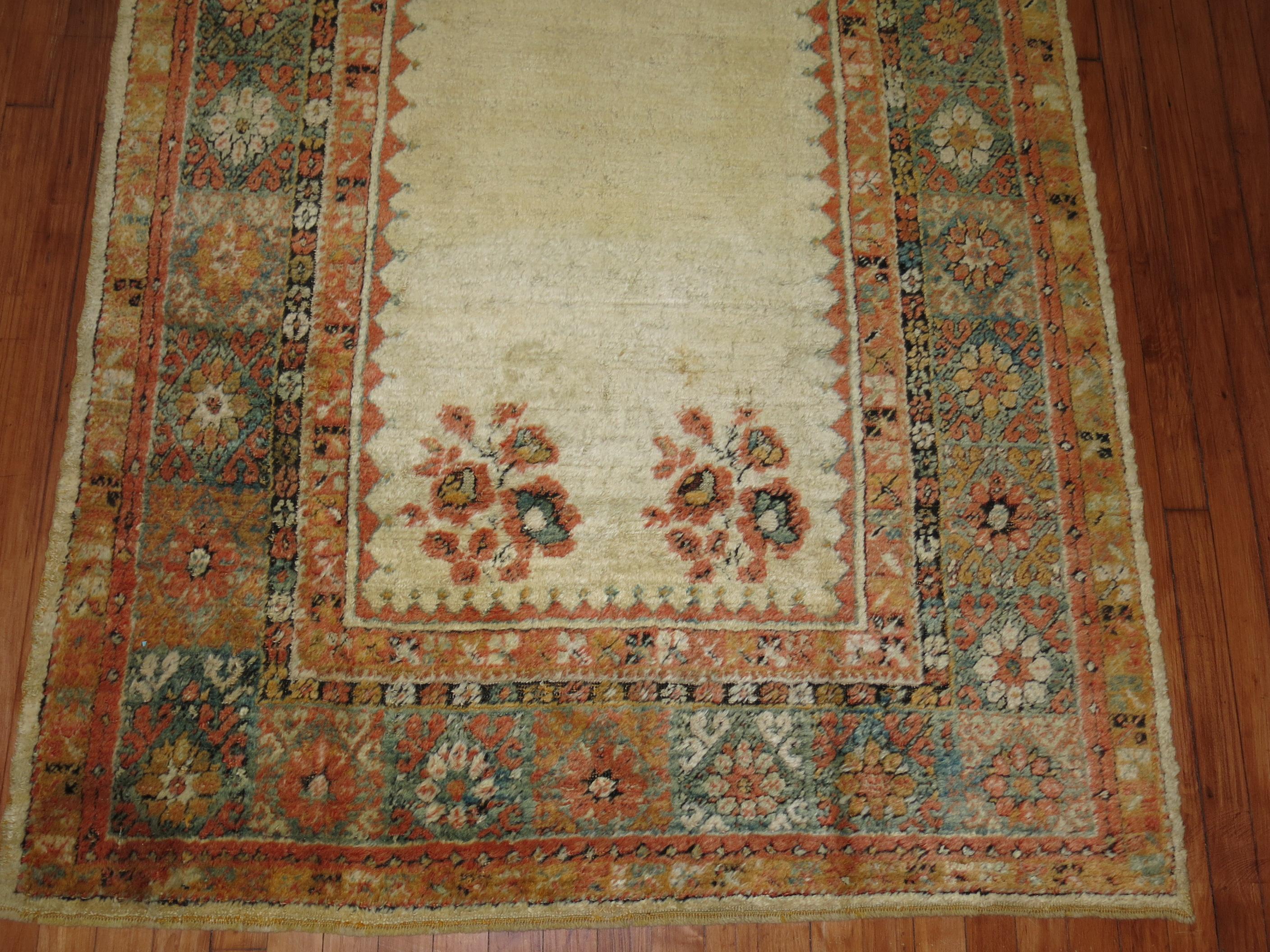 An early 20th century angora wool Oushak rug with a ivory colored field with other subtle warm accents in orange and green. This is a genuine piece woven with angora goat wool and its an antique. There is no noticeable repairs or any condition