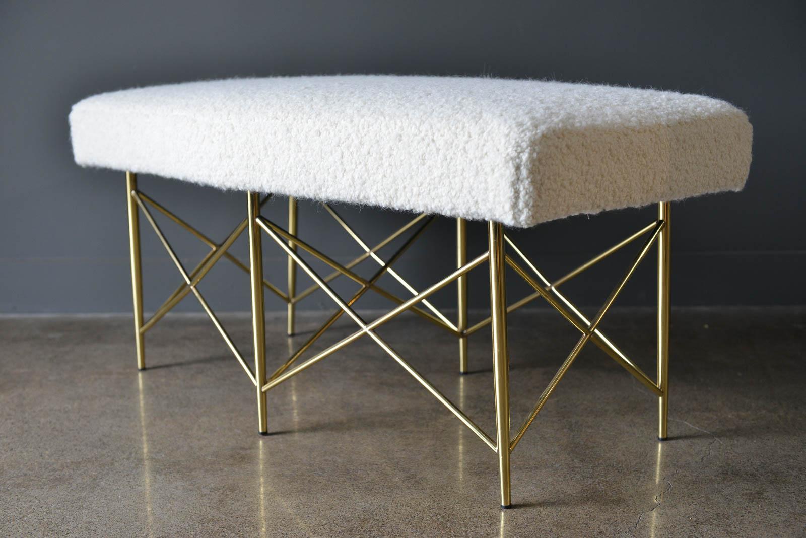 Ivory Bouclé and brass X-base ottoman or bench, circa 1970. Professionally recovered in beautiful soft ivory or cream wool bouclé fabric with new foam. Bench base is brass and has been polished. Beautiful trapezoid shape, could be used at the end of