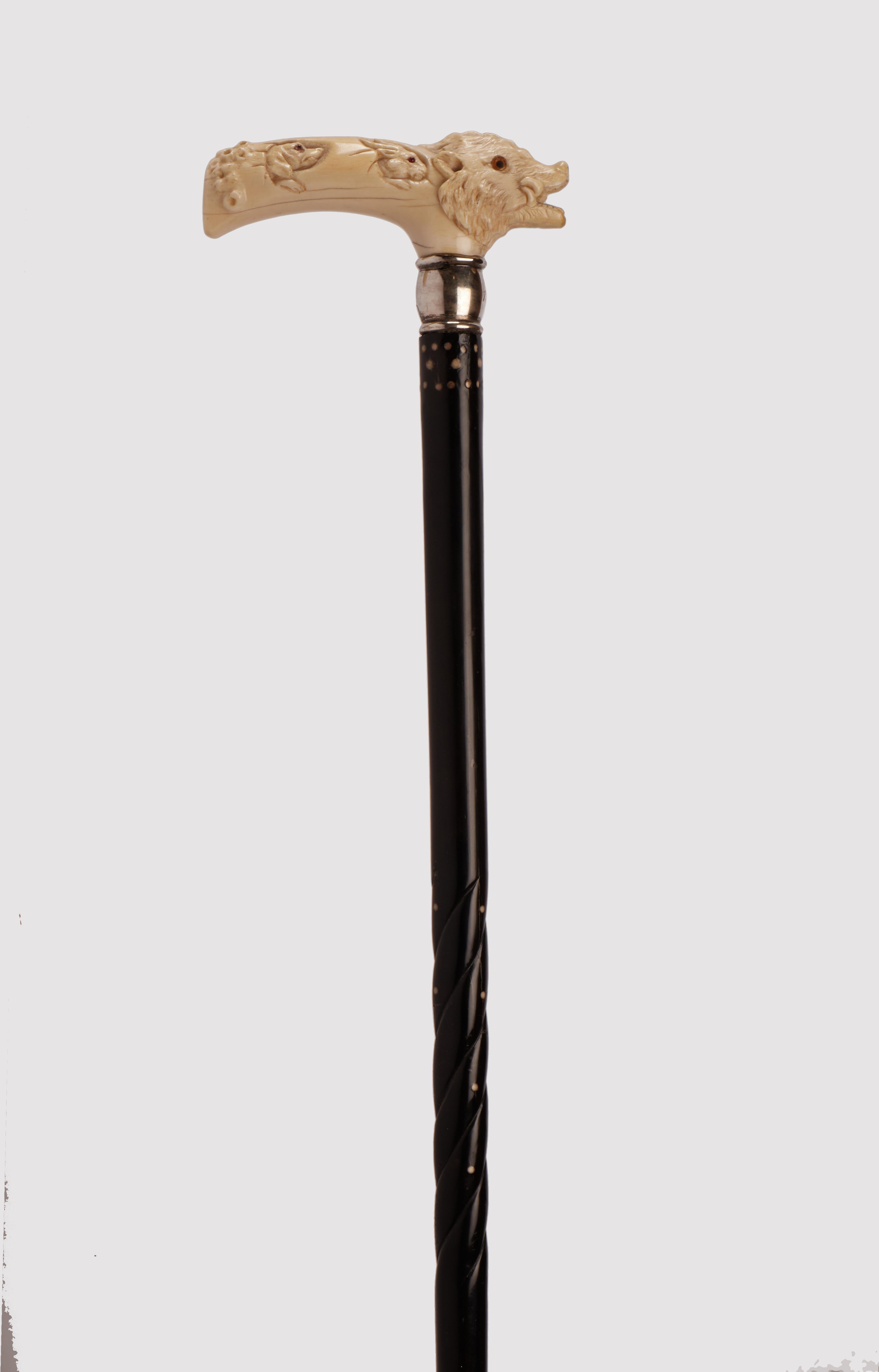 Walking stick: ivory carved handle depicting a wild boar with arrow in its mouth, a dog head, an hare and a native america hunting a boar. Sulphur glass eyes. Shaft ebony wood with ivory knobs. Silver ring. Metal ferrule. USA circa 1910. 
(SHIP TO
