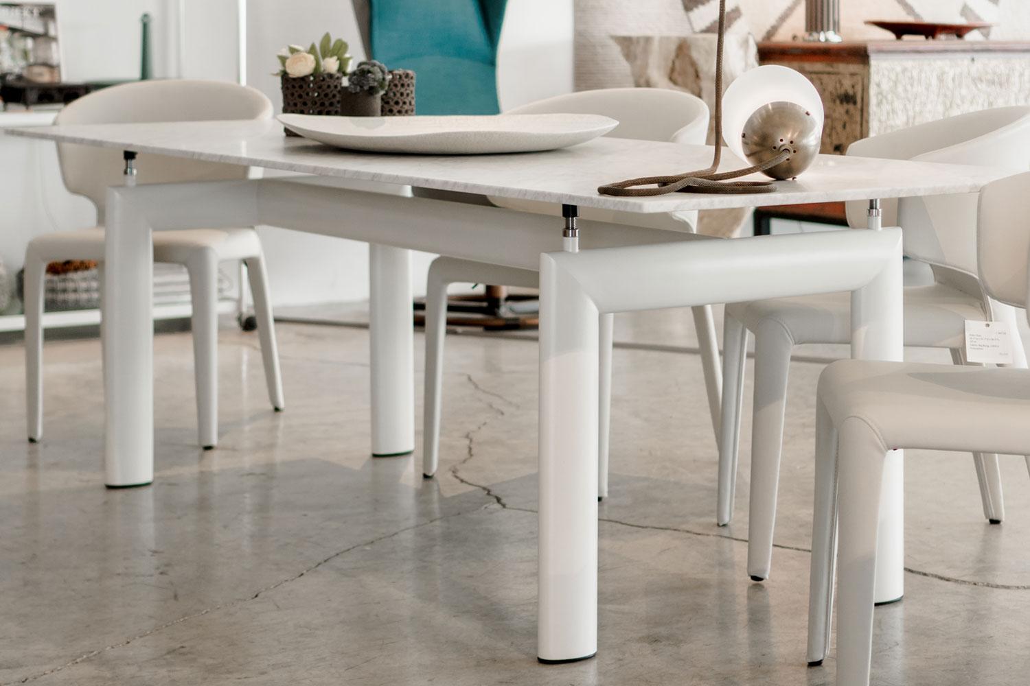 The base of this LC 6 table from Cassina has four supporting points with steel threaded shanks, permitting height adjustment up to 2”. The Carrara top with ivory enameled base makes this table a versatile kitchen or dining table. Please note