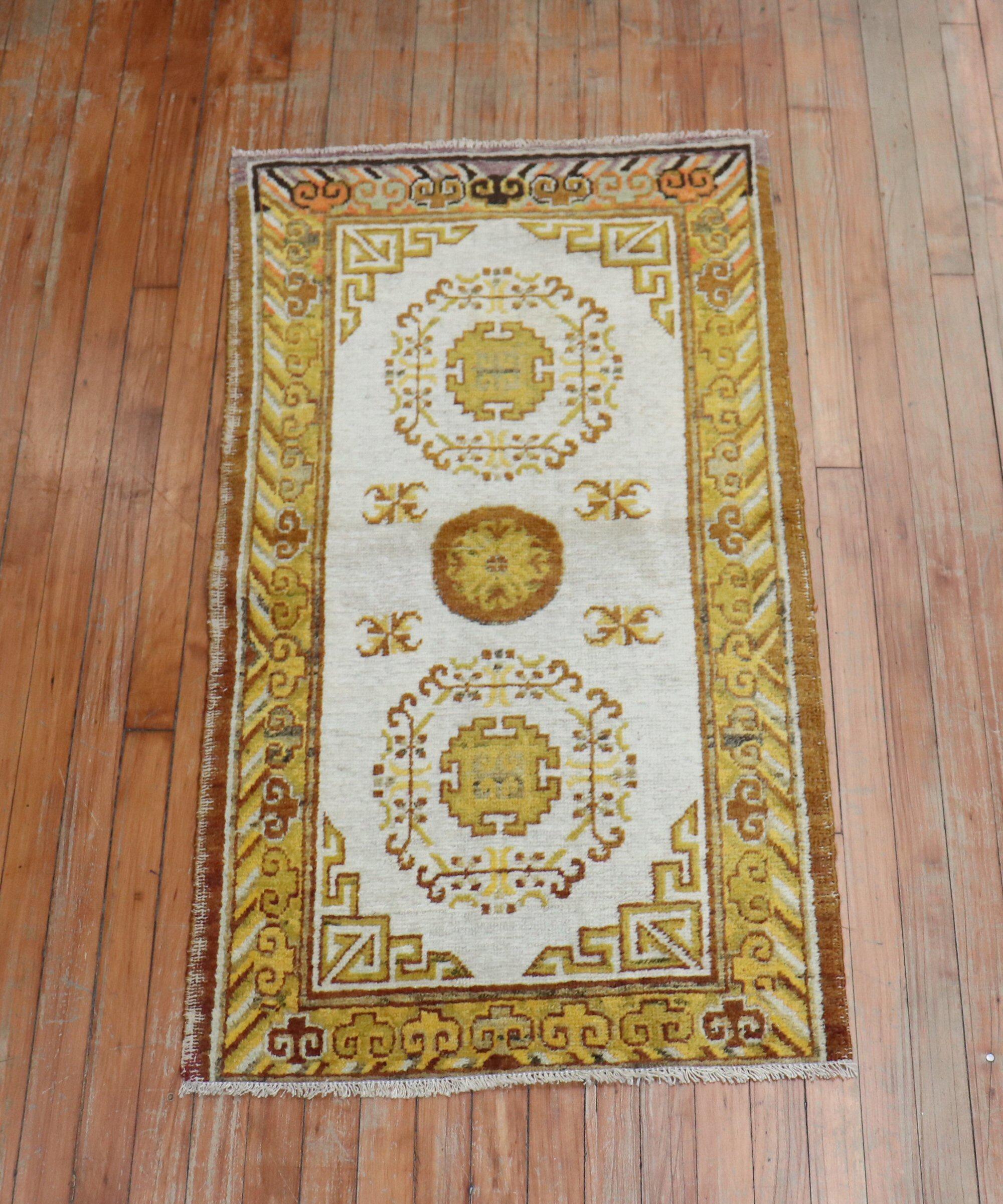 A late 19th century Khotan scatter rug. Field is ivory, gold and brown main accent colors. 1 end border has pops of lavender and orange.

Measures: 2'4