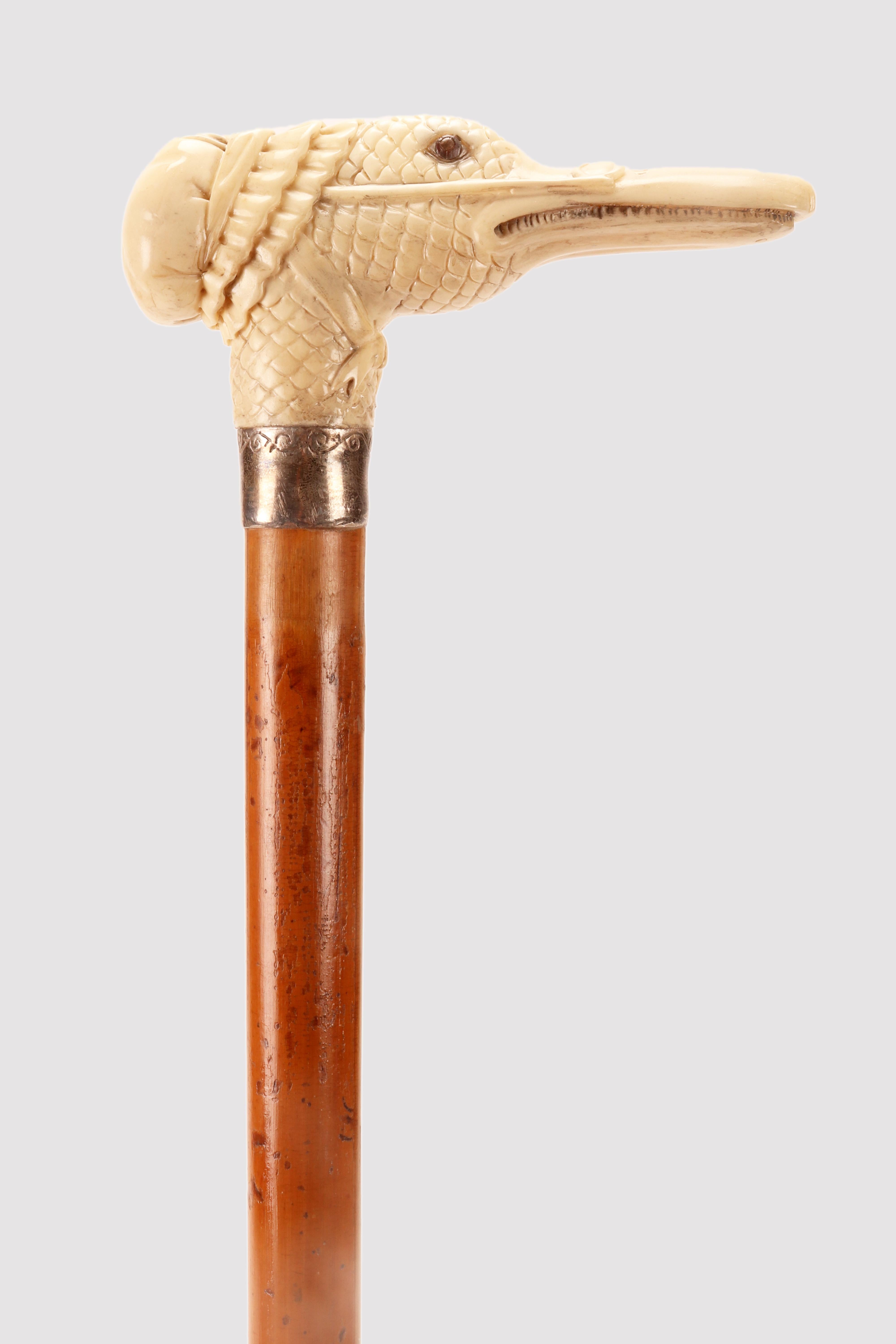Walking stick: Ivory carved handle T shape, depicting a goose head, wearing glasses and a nightcap. Silver ring. Sulphur glass eyes. Malacca wood shaft. Metal ferule. Austria circa 1880.                                                               