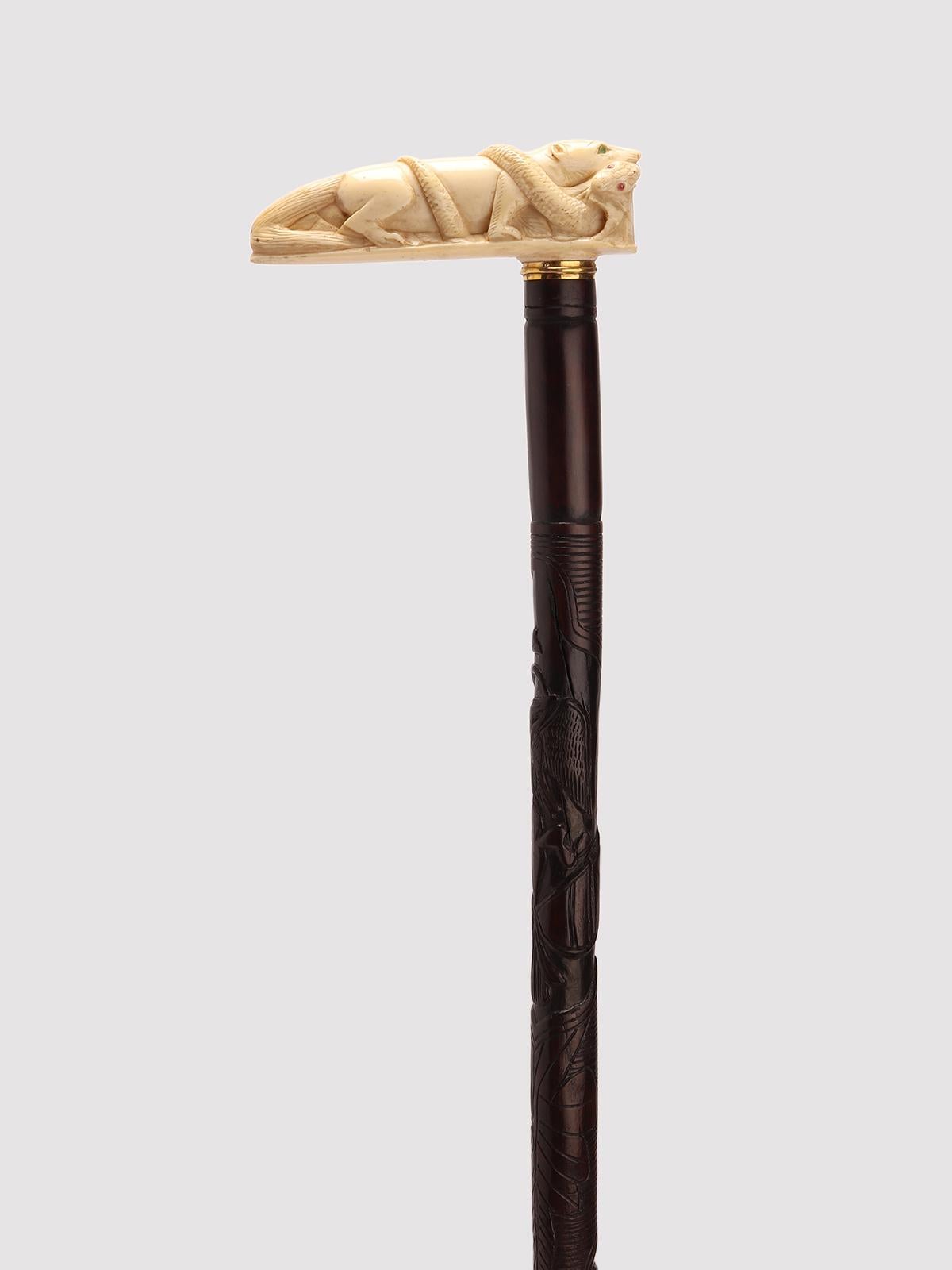 Bastone da passeggio, pomello in avorio intagliato, raffigurante una mangusta con un serpente in bocca. Occhi di smeraldo e rubino. Fascia in oro 18 carati. Il barile è scolpito e intagliato da un singolo ramo di acero patinato. La punta, realizzata