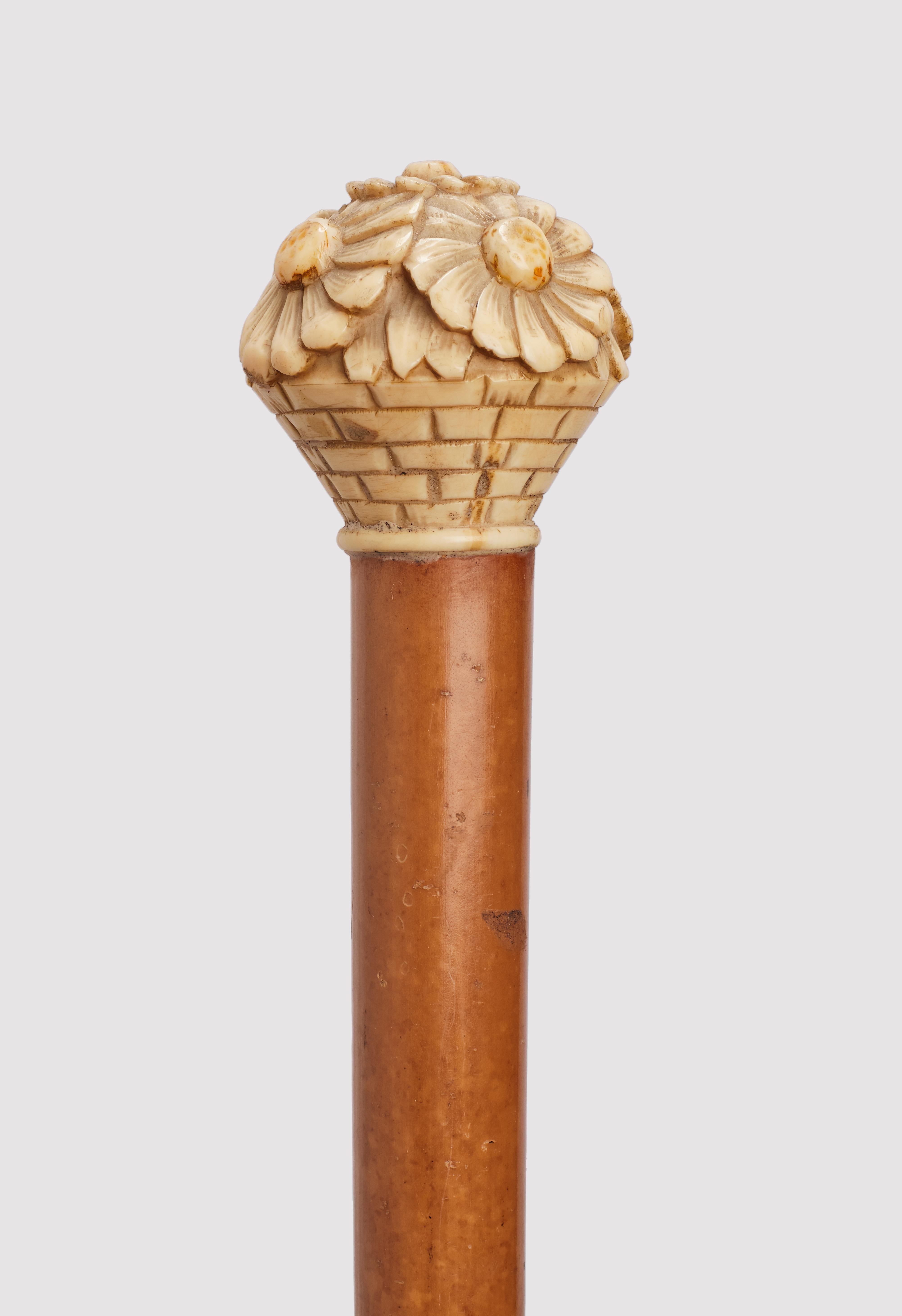 Bastón: pomo de marfil tallado que representa un jarrón con margaritas. Fuste de madera de Malaca. Virola metálica. Francia, hacia 1915. (SÓLO ENVÍO A LA UE)