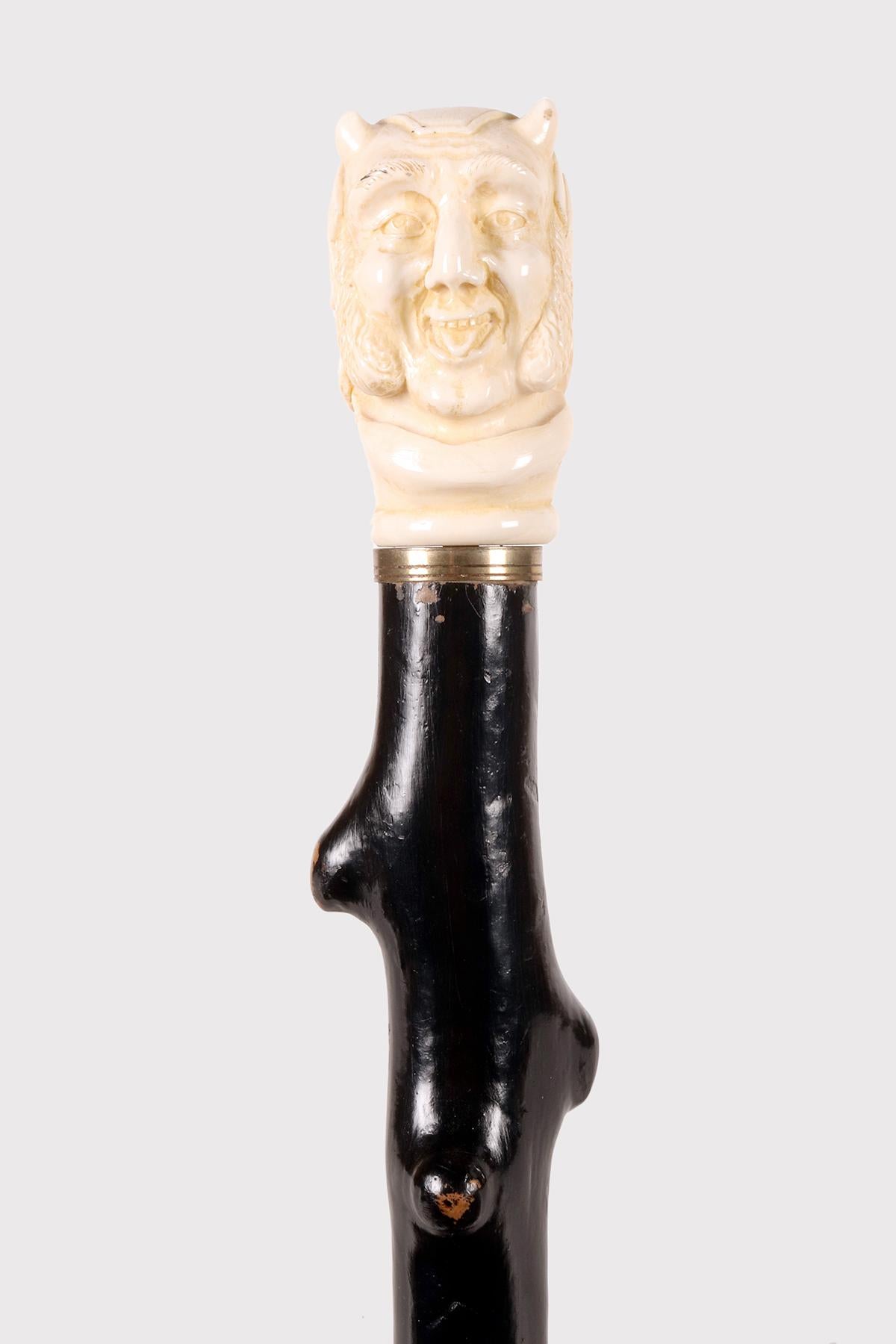 Walking stick: ivory carved handle. The handle depicts a caricatural face of Mephistopheles. Ebonized fruitwood shaft rustic shape. Silver ring. Metal ferrule. England circa 1870. (SHIP TO EU ONLY)
