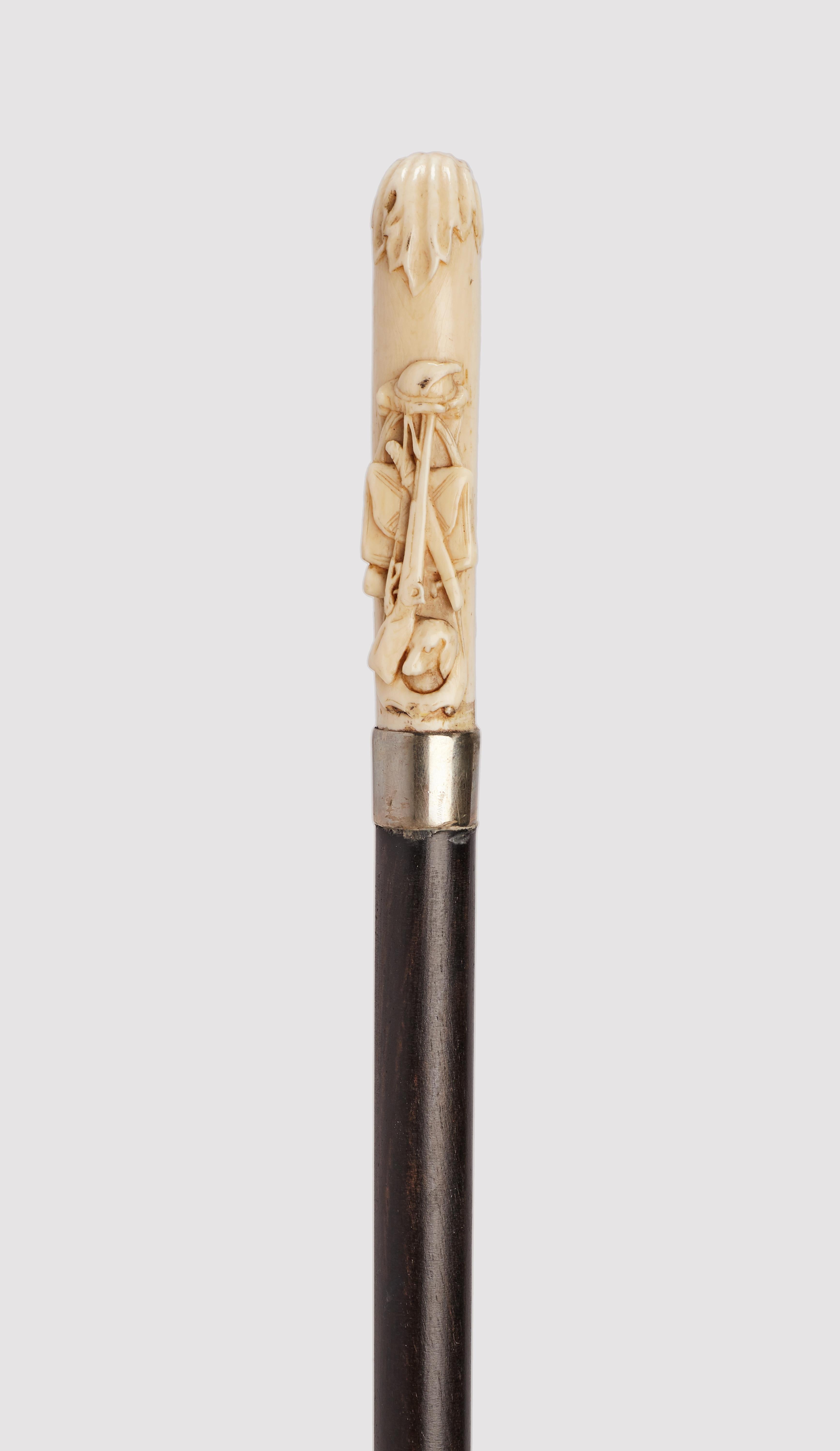 Canne : poignée sculptée en ivoire. La poignée représente un fusil, une tête de chien et un sac de chasse.  Manche en bois d'ébène. Bague en argent. Virole en ivoire. Angleterre vers 1880.
(LIVRAISON DANS L'UE UNIQUEMENT)