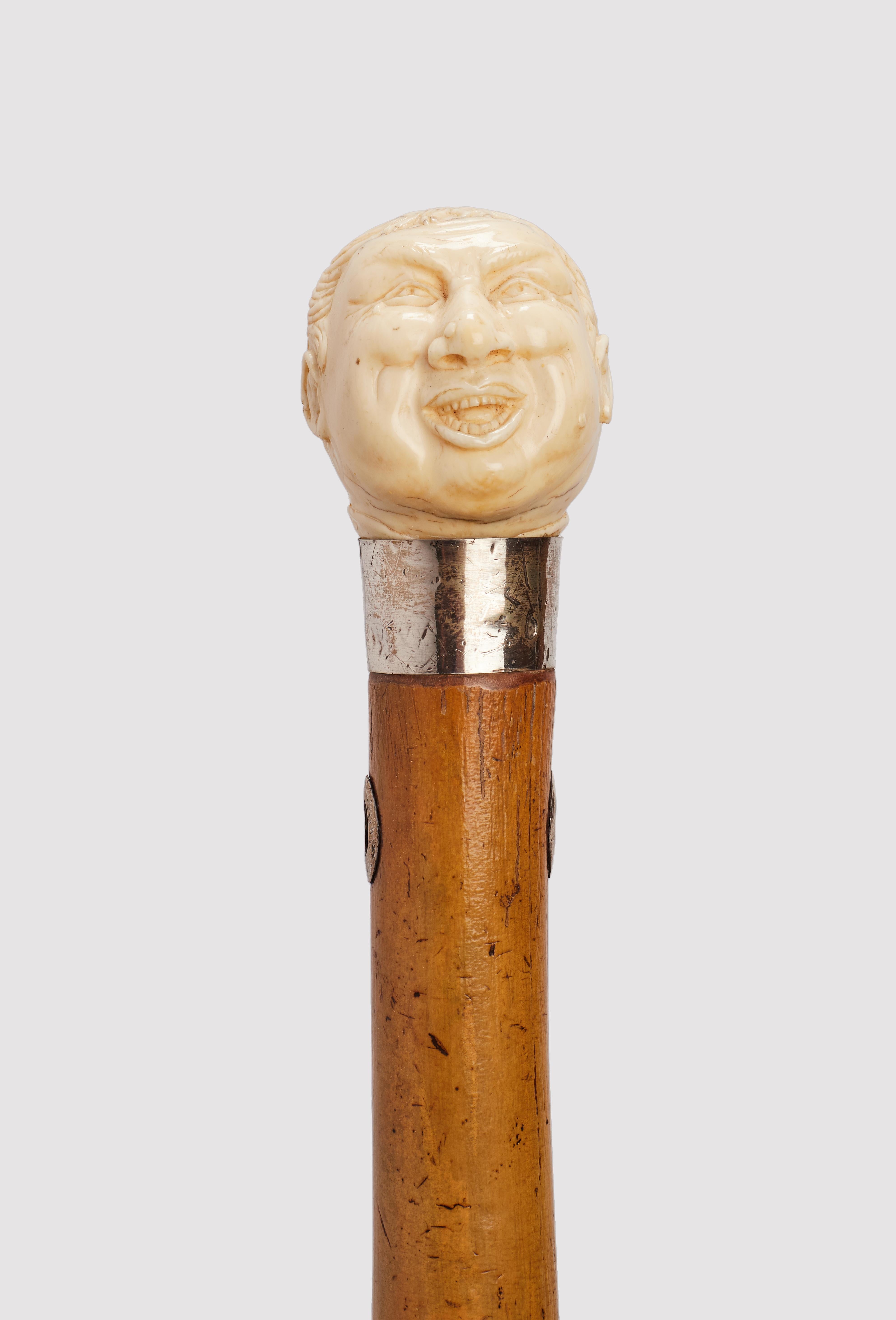 Bastone da passeggio: pomello in avorio. Il manico raffigura la testa di un monaco che ride. Canna di bambù, con occhielli d'argento per il foro passante del laccio. Anello in argento. Inghilterra, circa 1880.
(SPEDIZIONE SOLO NELL'UE)
