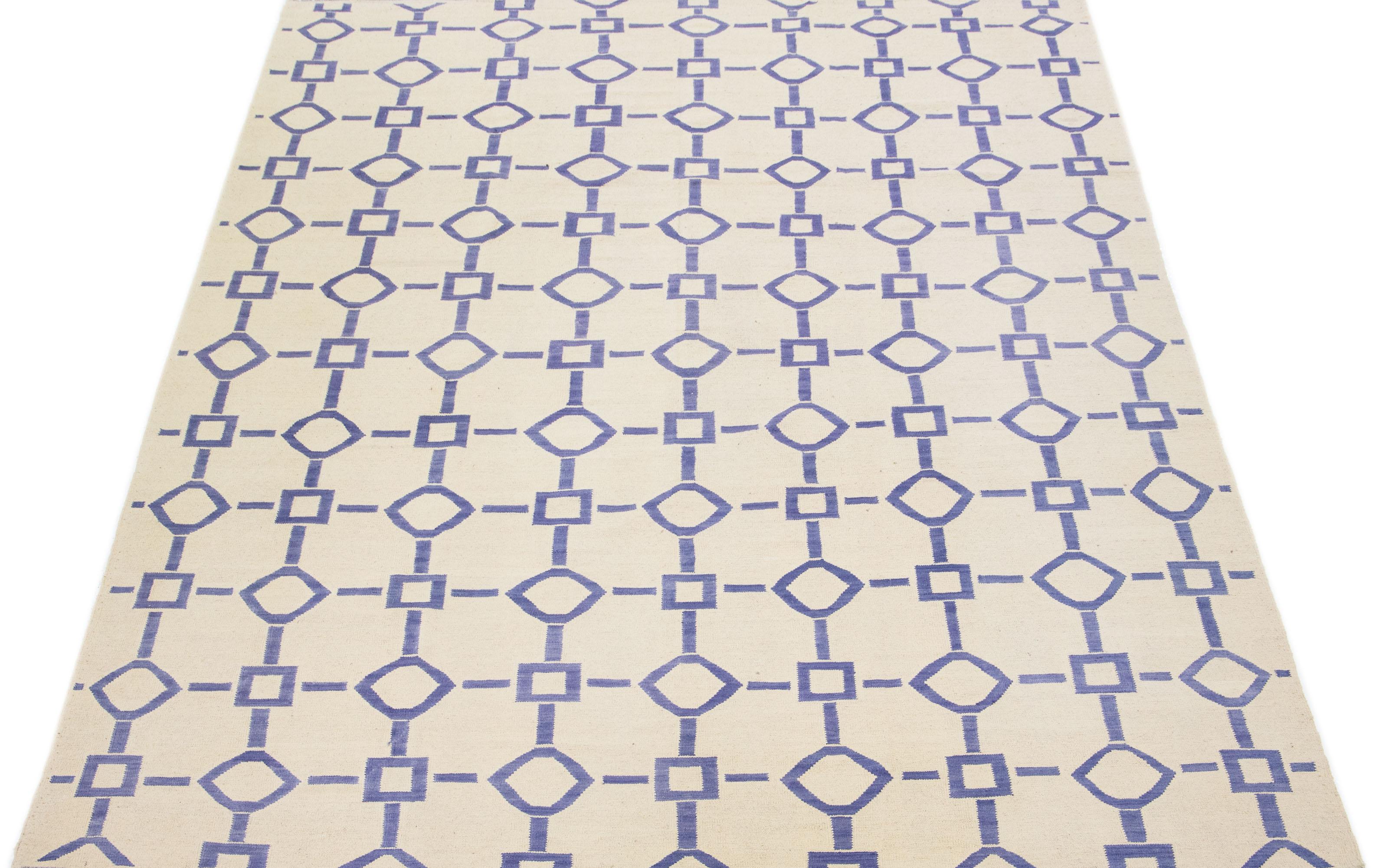 This modern Kilim rug exudes elegance with its finely woven flat-weave wool, presented in a captivating ivory hue complemented by a stunning geometric pattern with accents of blue.

This rug measures 9' x 12'2