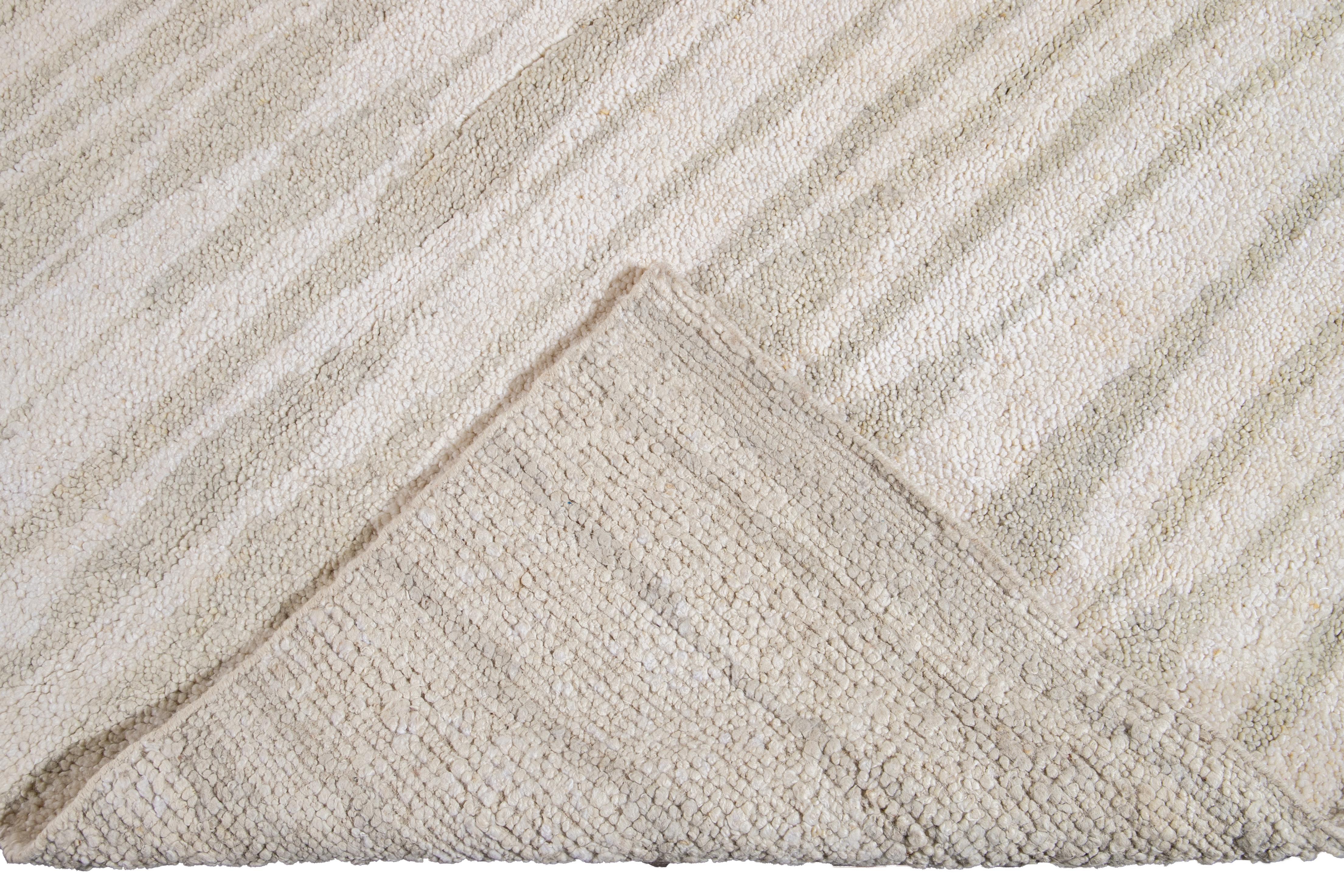 Beautiful Moroccan- style handmade wool rug with an ivory field. This Moroccan rug has accents in gray in a gorgeous all-over geometric striped design.

This rug measures: 12'3